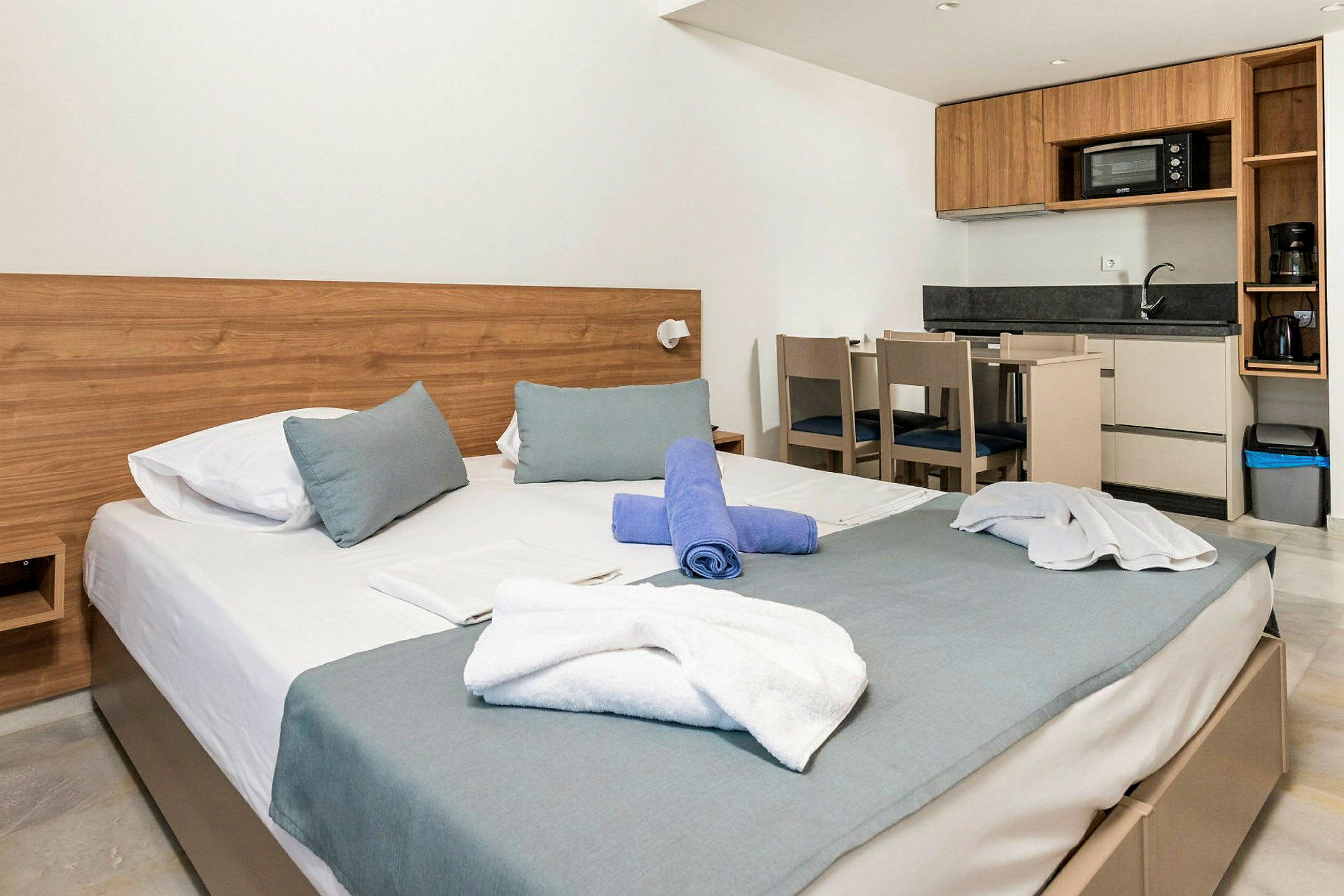 Moderne indrettet hotelværelse med seng, køkken og spisebord. (AI-genereret tekst)