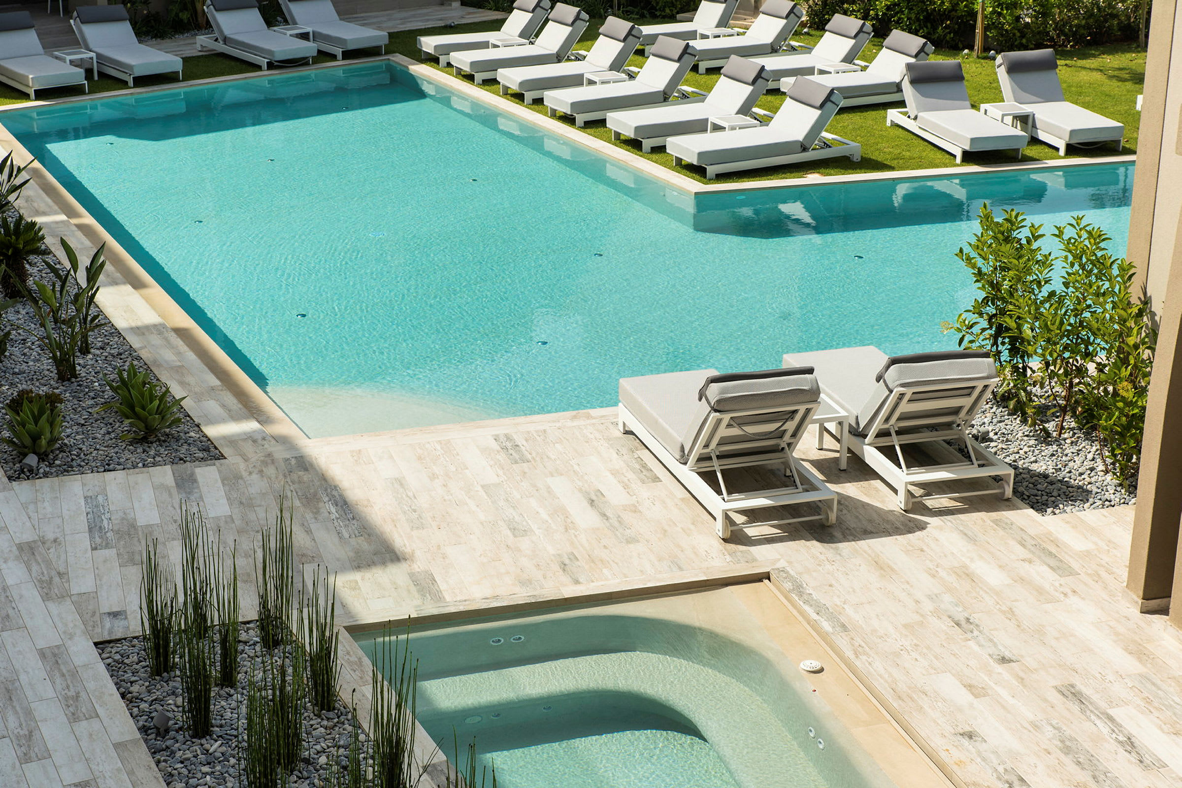 Udendørs swimmingpool med liggestole omkring. (AI-genereret tekst)