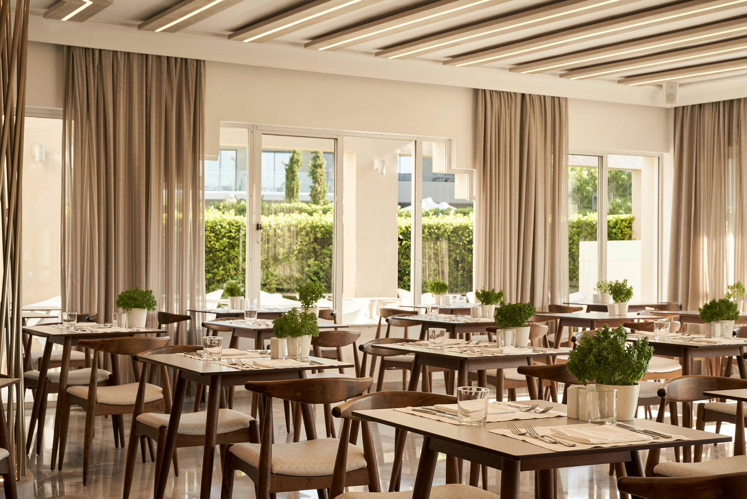 Et moderne indrettet restaurantområde med borde og stole i træ samt urtepotter. (AI-genereret tekst)