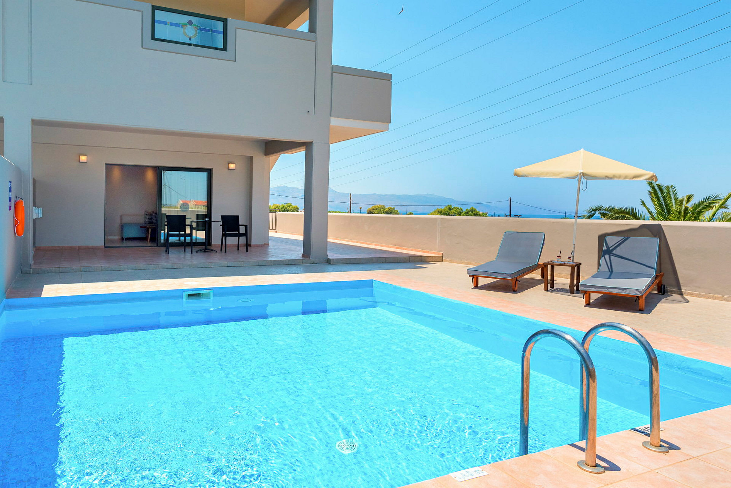 En terrasse med en swimmingpool, liggestole og parasol. (AI-genereret tekst)