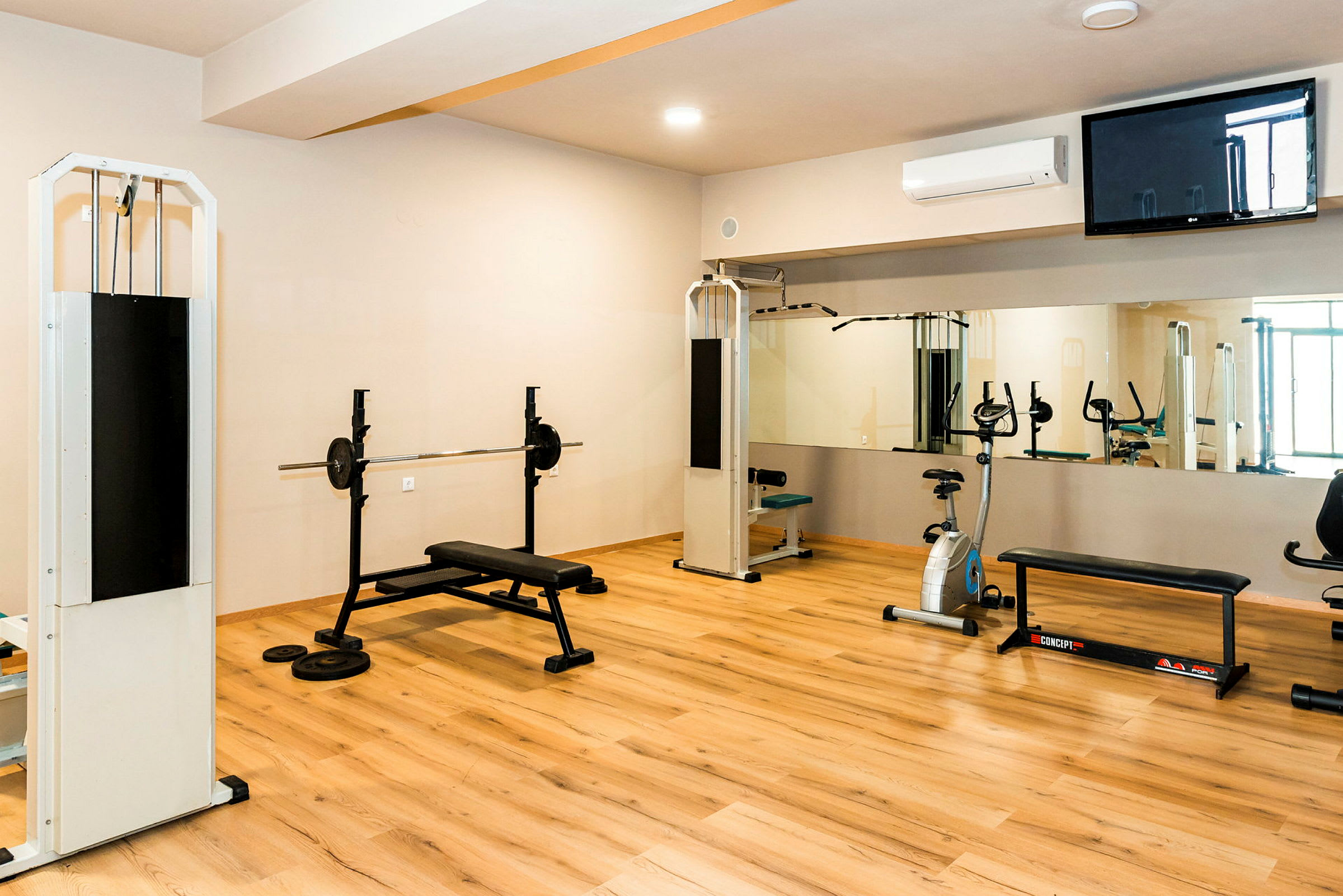 Et fitnesscenter med træningsudstyr, herunder bænkpres, kabelmaskiner og motionscykel. (AI-genereret tekst)