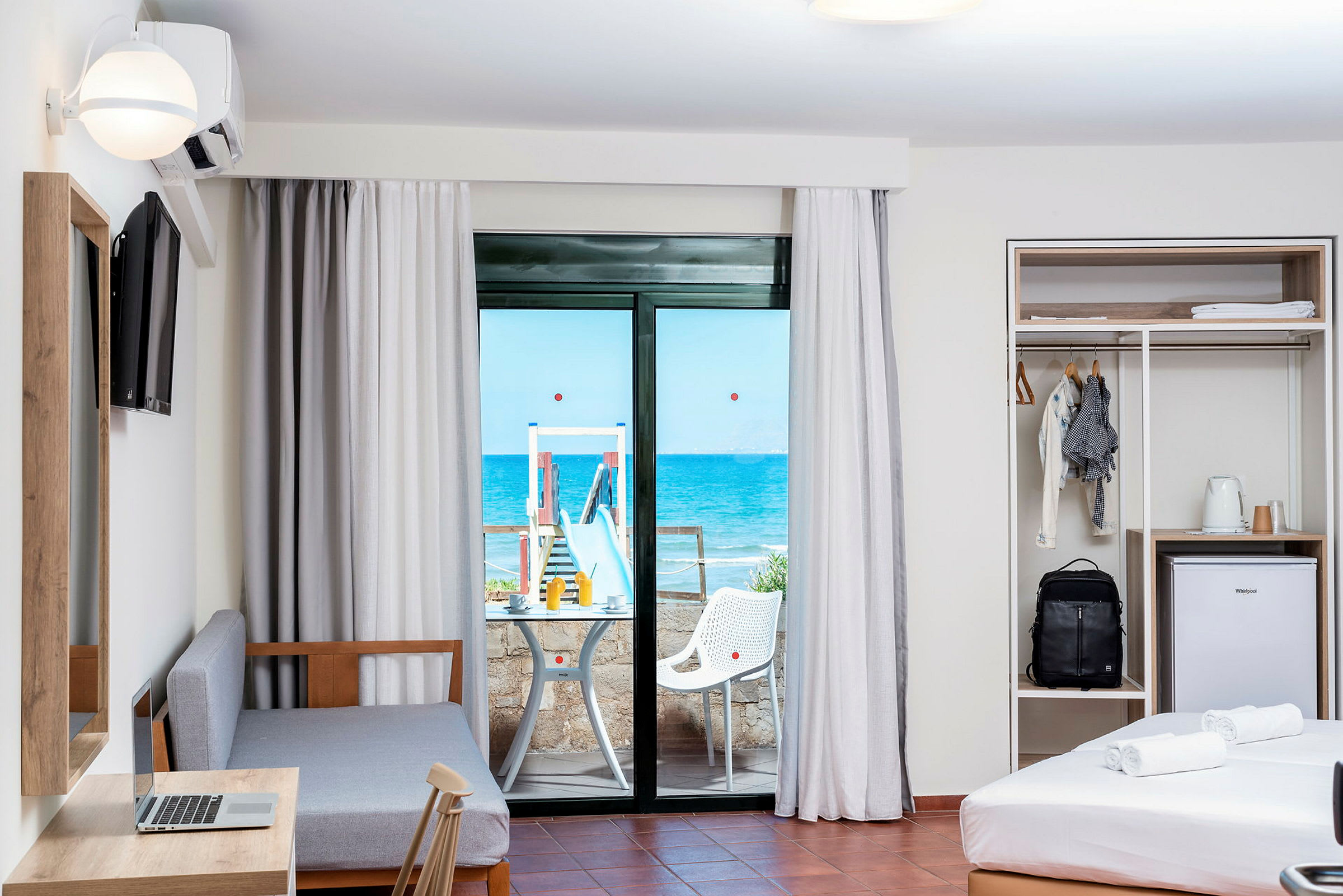 Et hotelværelse med en balkon med udsigt til havet. (AI-genereret tekst)