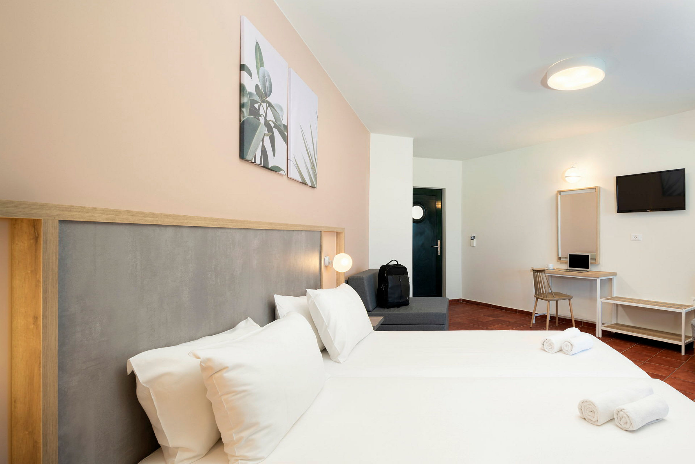 Hotelværelse med dobbeltseng, siddeområde, skrivebord og TV. (AI-genereret tekst)