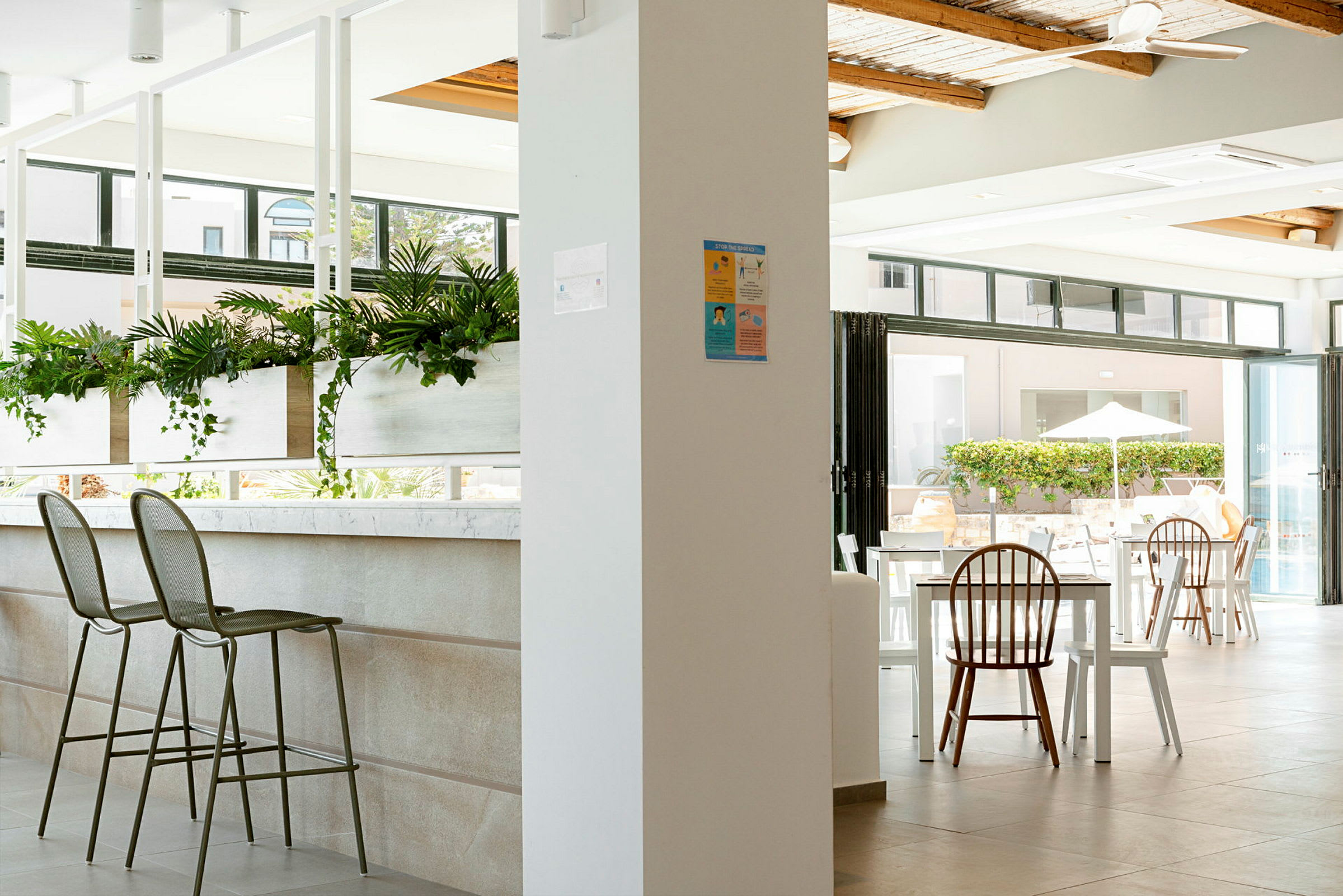 Interiør af en moderne og lys restaurant med siddepladser og grønne planter. (AI-genereret tekst)