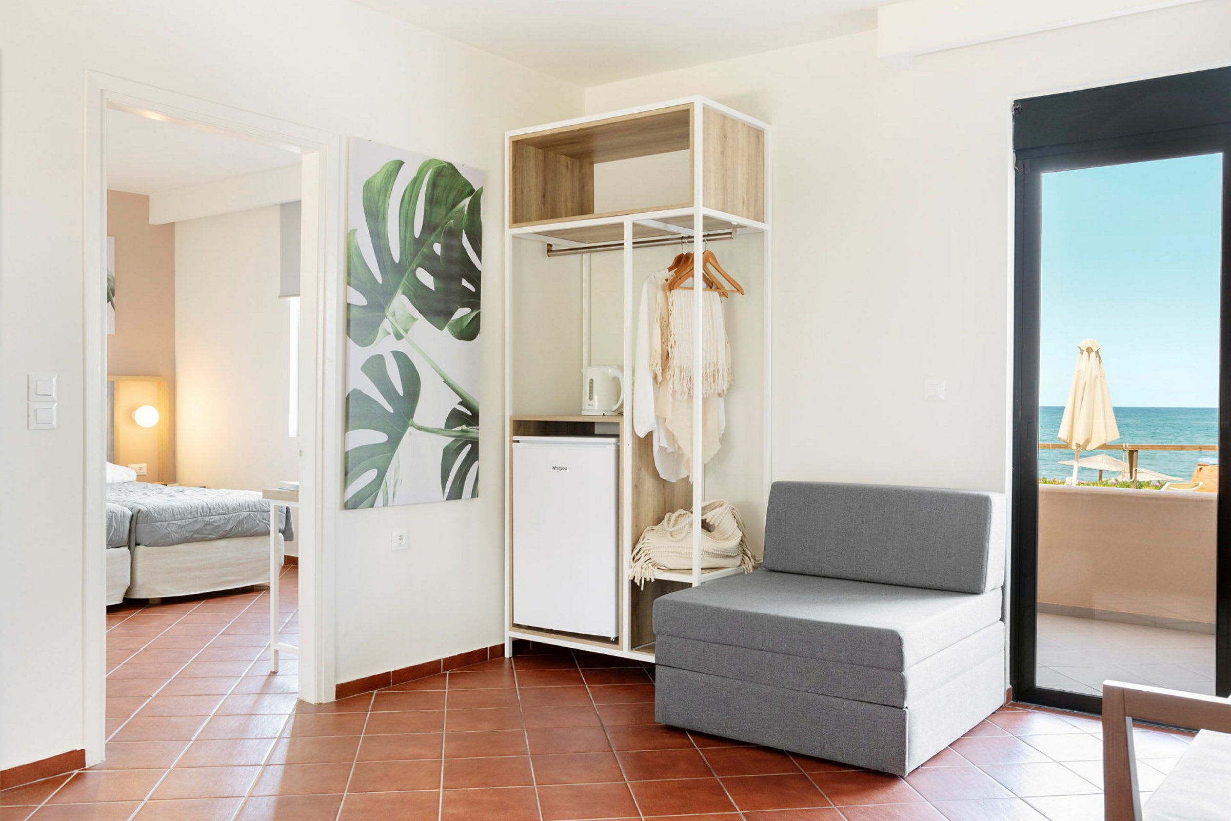 Moderne hotelværelse med siddeplads, åben garderobe og havudsigt. (AI-genereret tekst)
