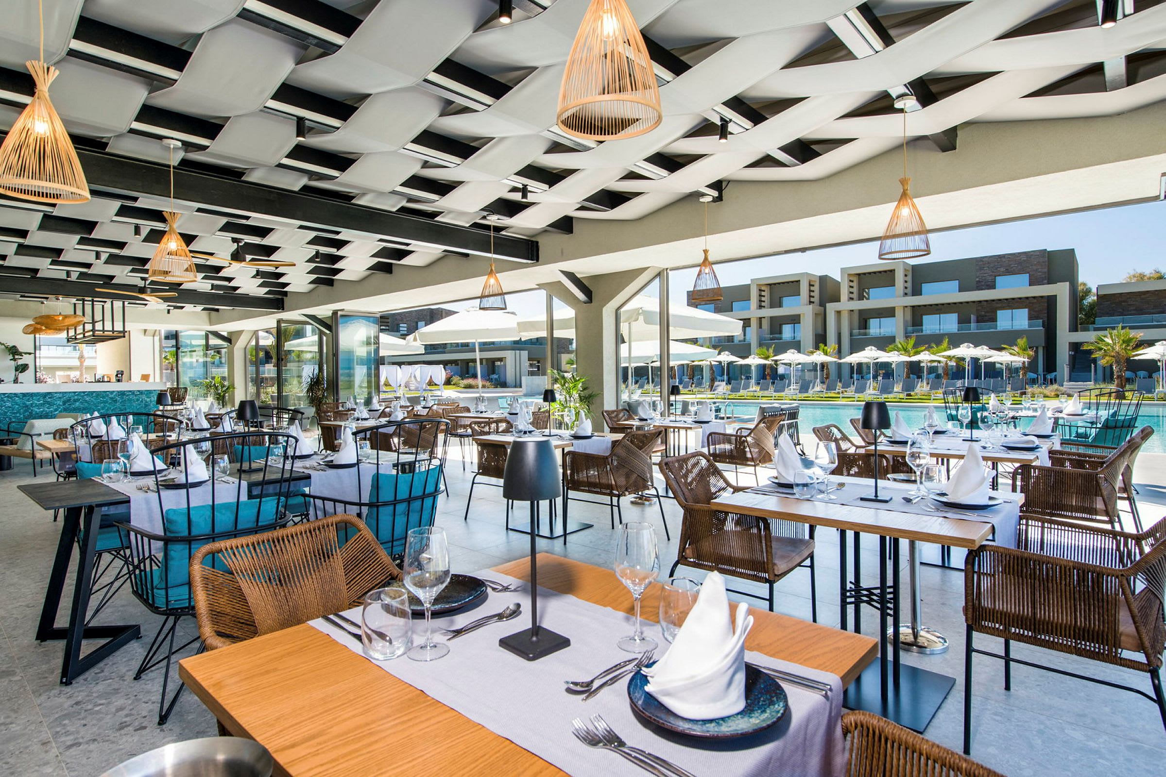 Restaurant med borde og stole nær en pool, med resortbygninger i baggrunden. (AI-genereret tekst)