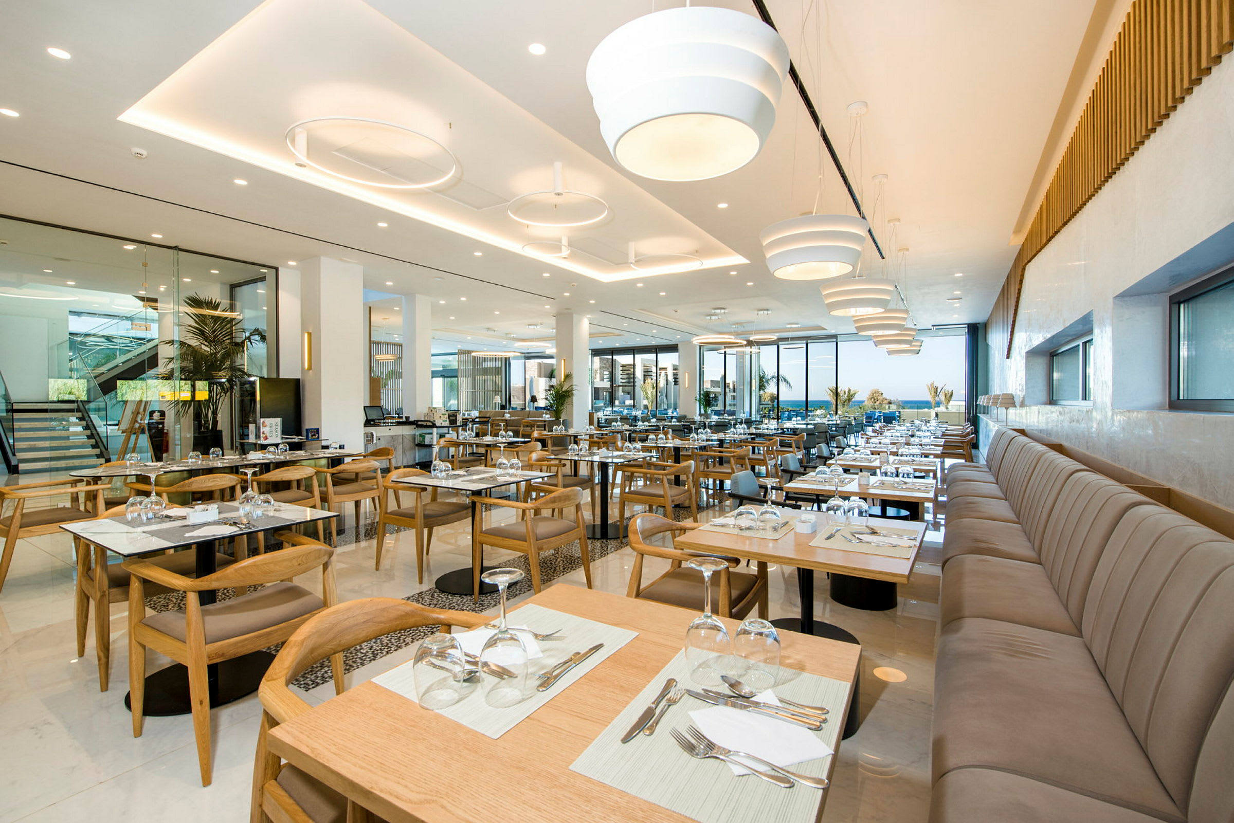 En moderne restaurant med opstillet borde og stole samt store vinduer. (AI-genereret tekst)