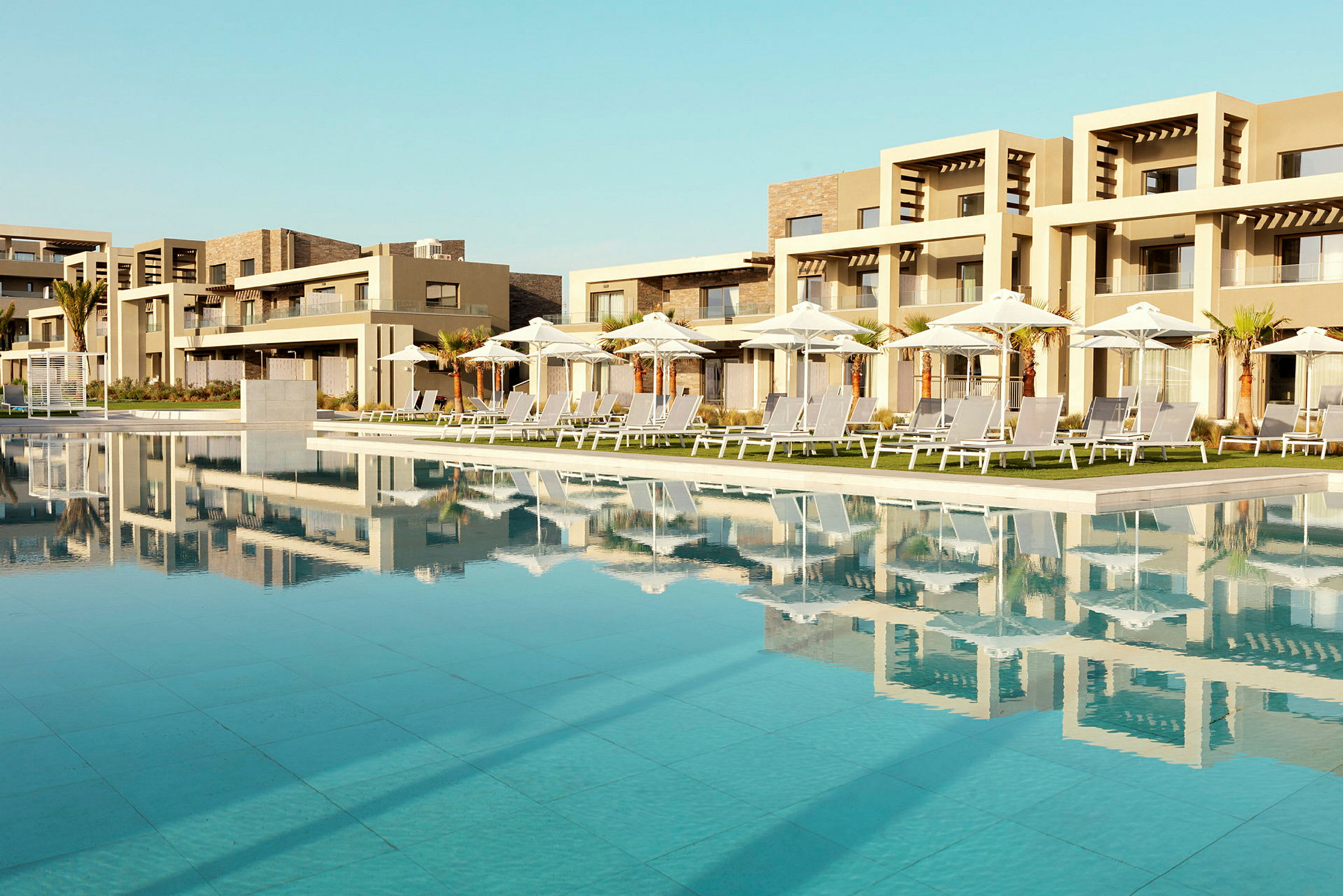 En pool med liggestole og parasoller ved et moderne hotel. (AI-genereret tekst)
