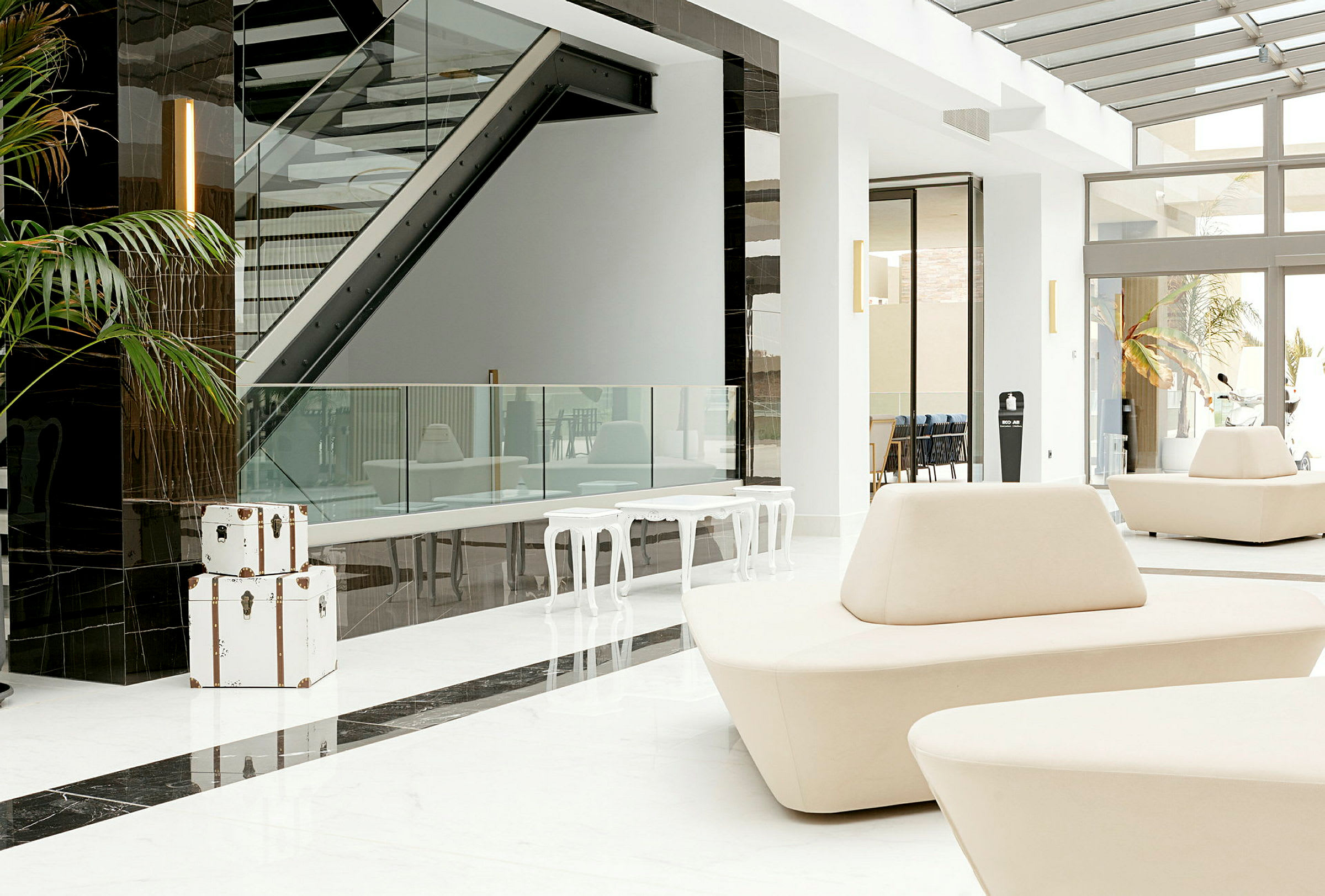 Lys og moderne hotellobby med hvide møbler og glasdetaljer. (AI-genereret tekst)