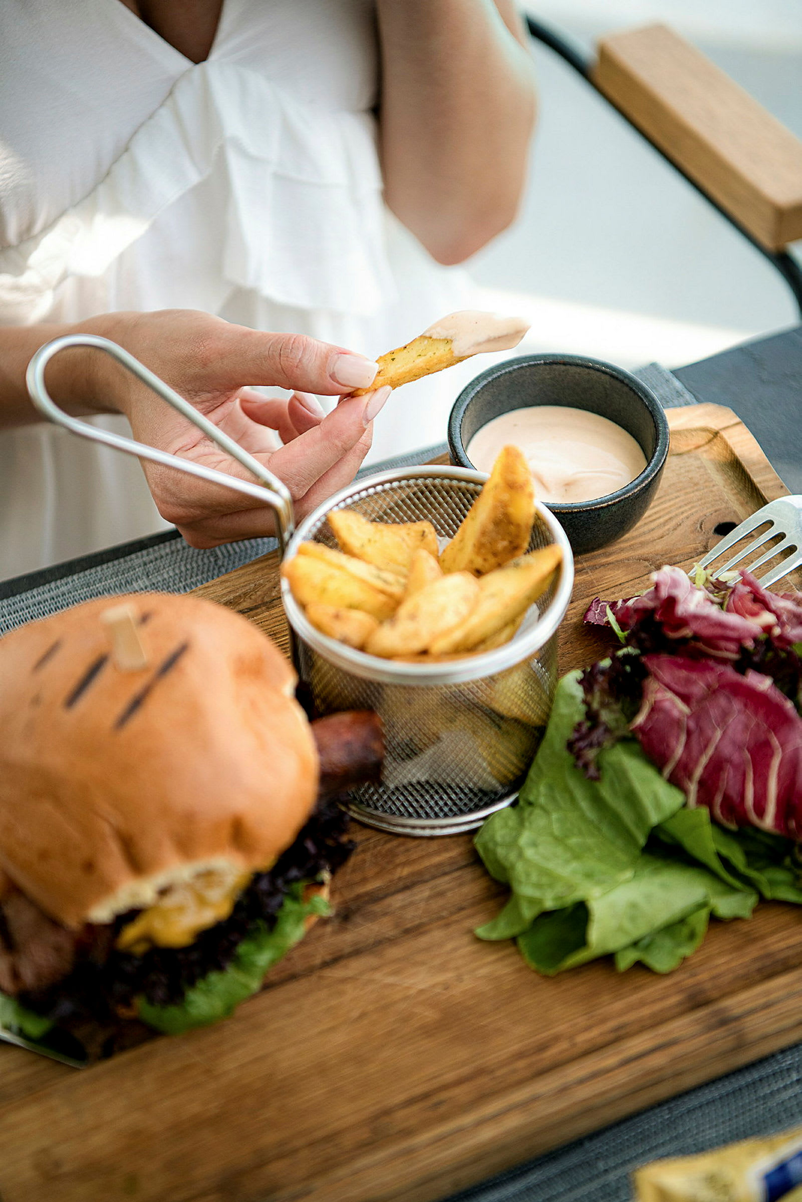 En person dypper en pommes frites i en skål med sauce. (AI-genereret tekst)