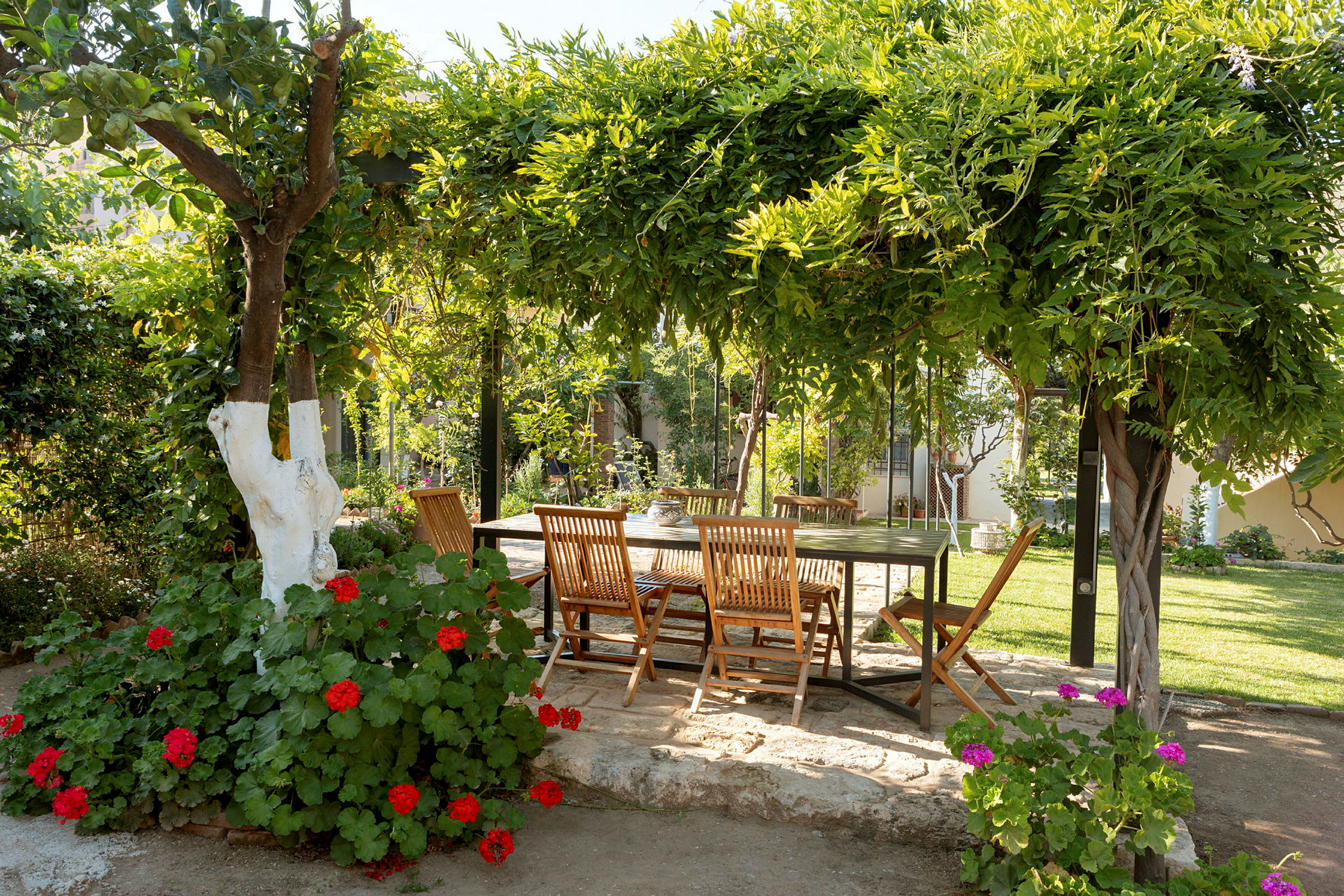 Have med et bord og stole under en frodig pergola. (AI-genereret tekst)