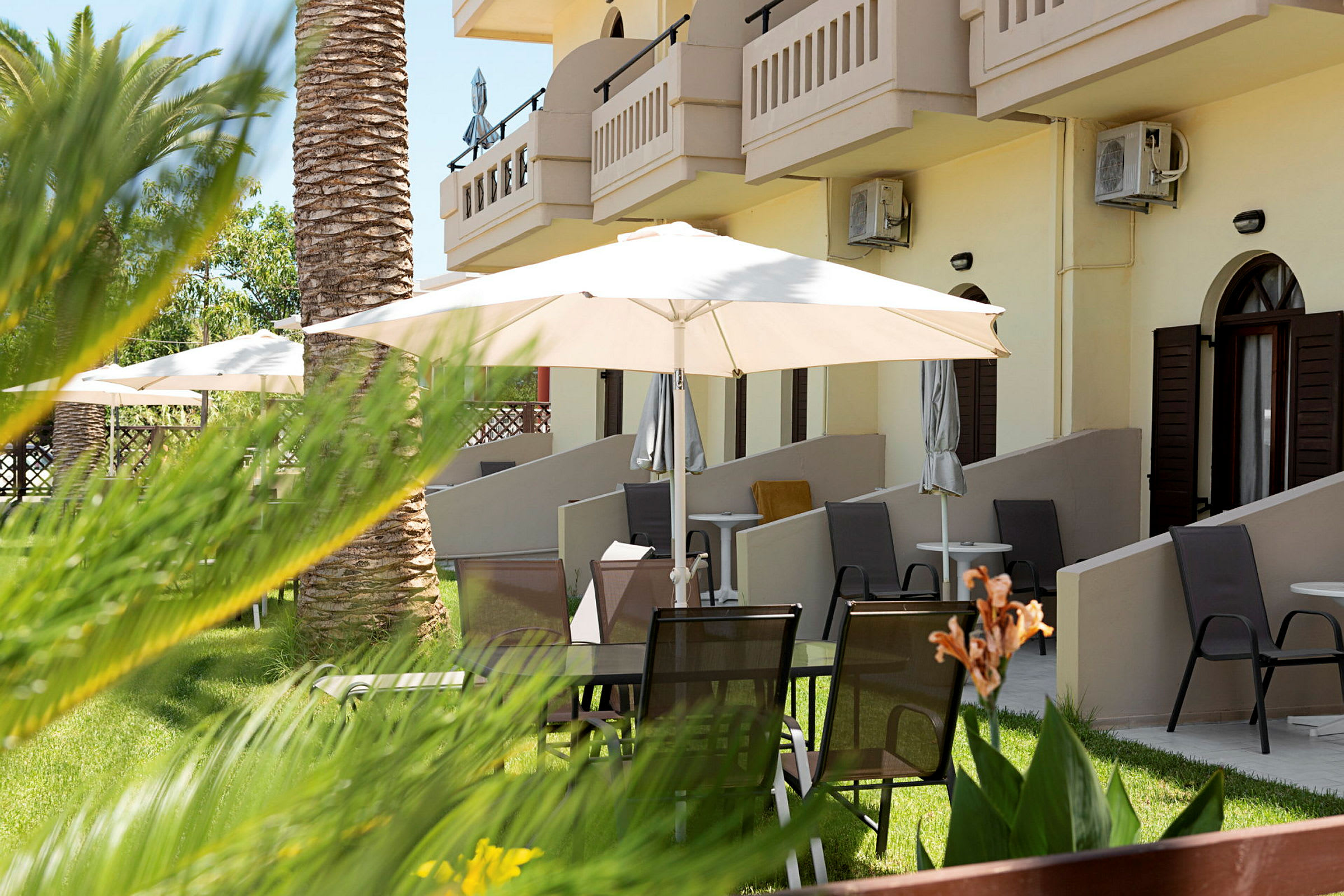 Terrasseområde med stole og parasoller foran bygningen. (AI-genereret tekst)