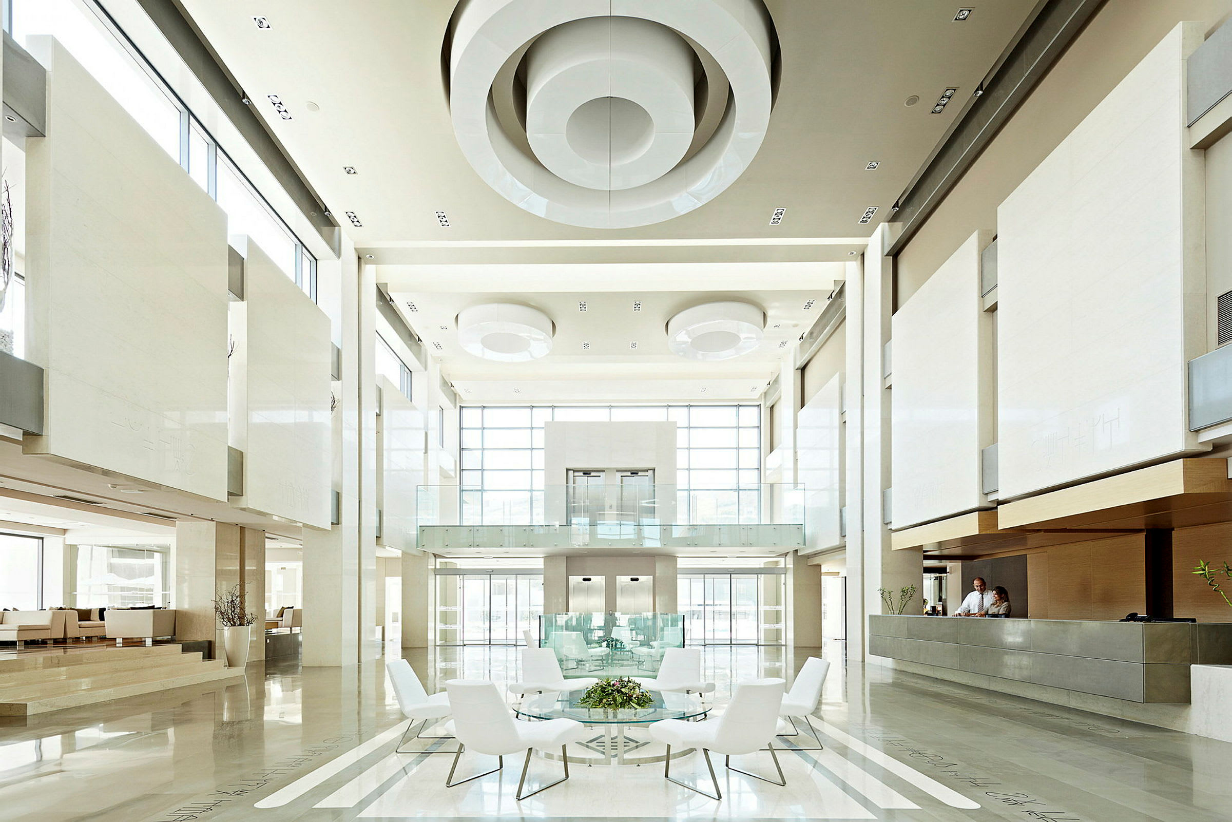 En moderne og lys hotellobby med store vinduer, højt til loftet, siddepladser og receptionsskranke. (AI-genereret tekst)