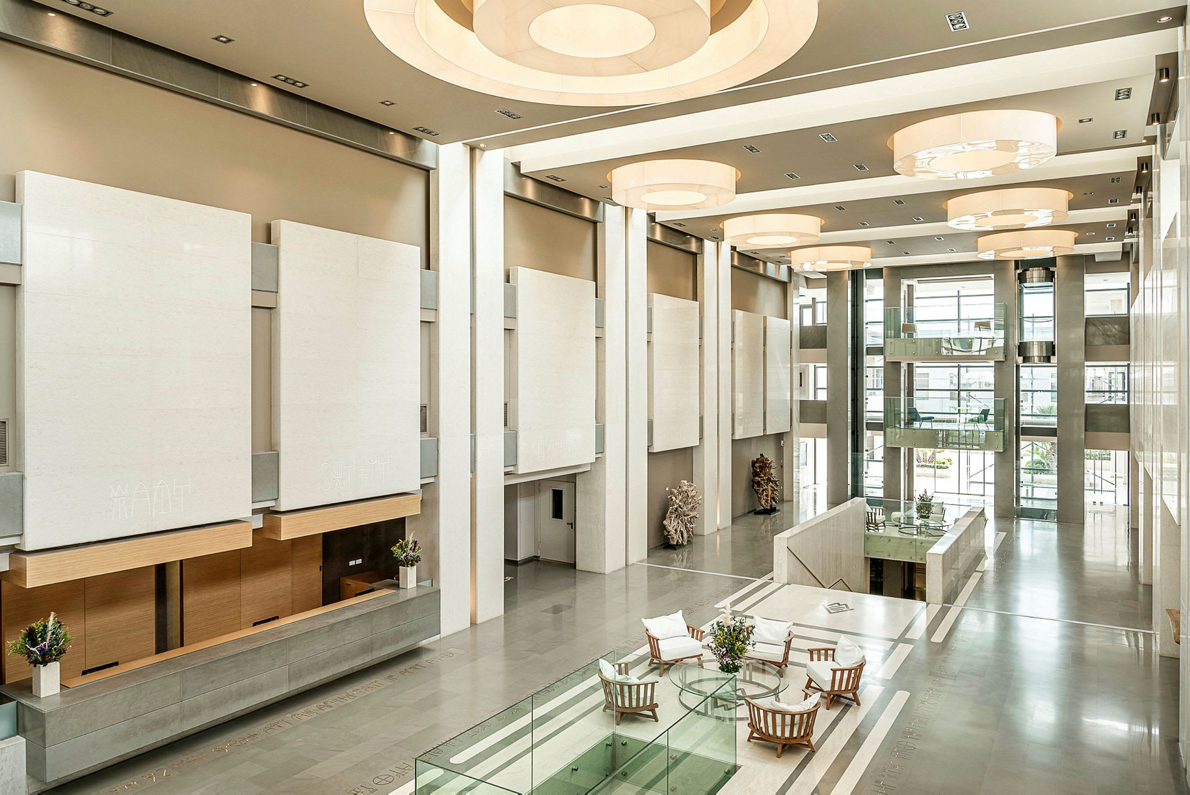 En lys og rummelig foyer med moderne indretningsdetaljer, glasværn og siddegrupper ved et bord. (AI-genereret tekst)