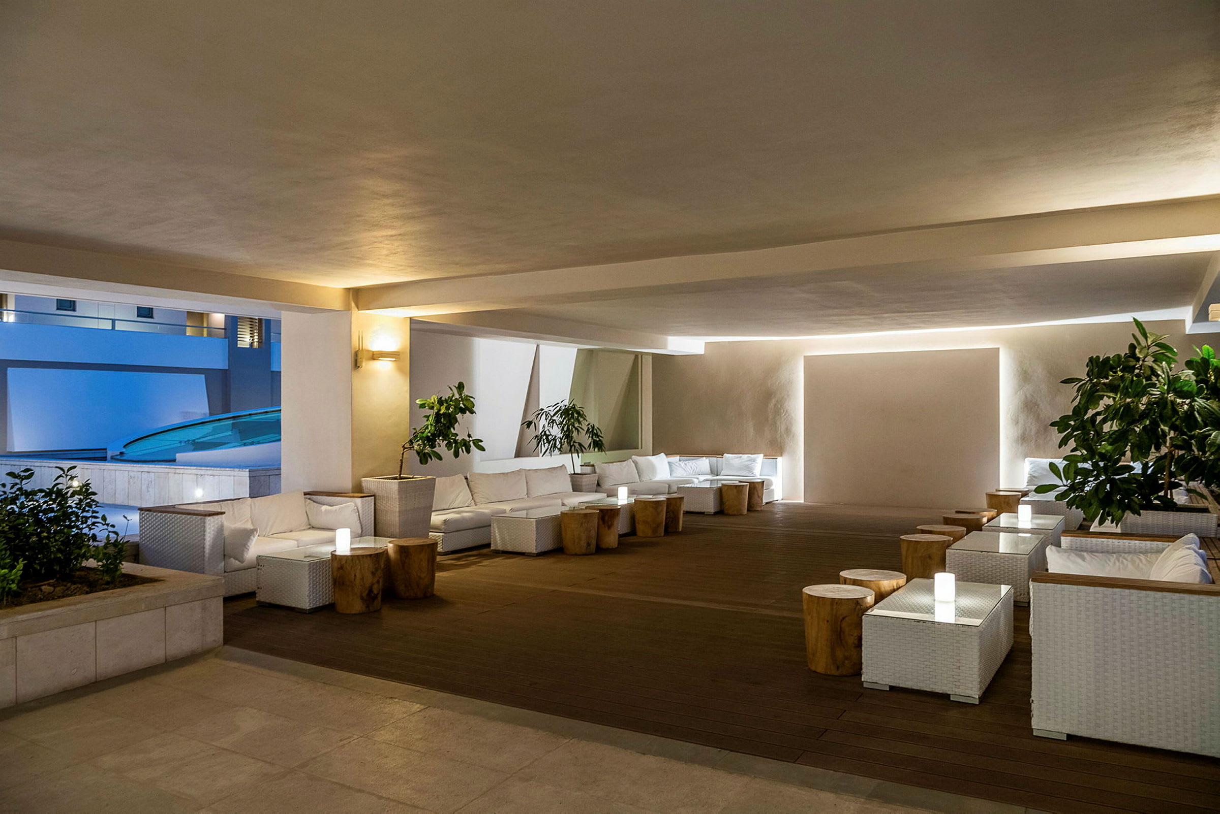 En moderne og elegant lounge med hvide møbler og træborde, omkranset af planter. (AI-genereret tekst)