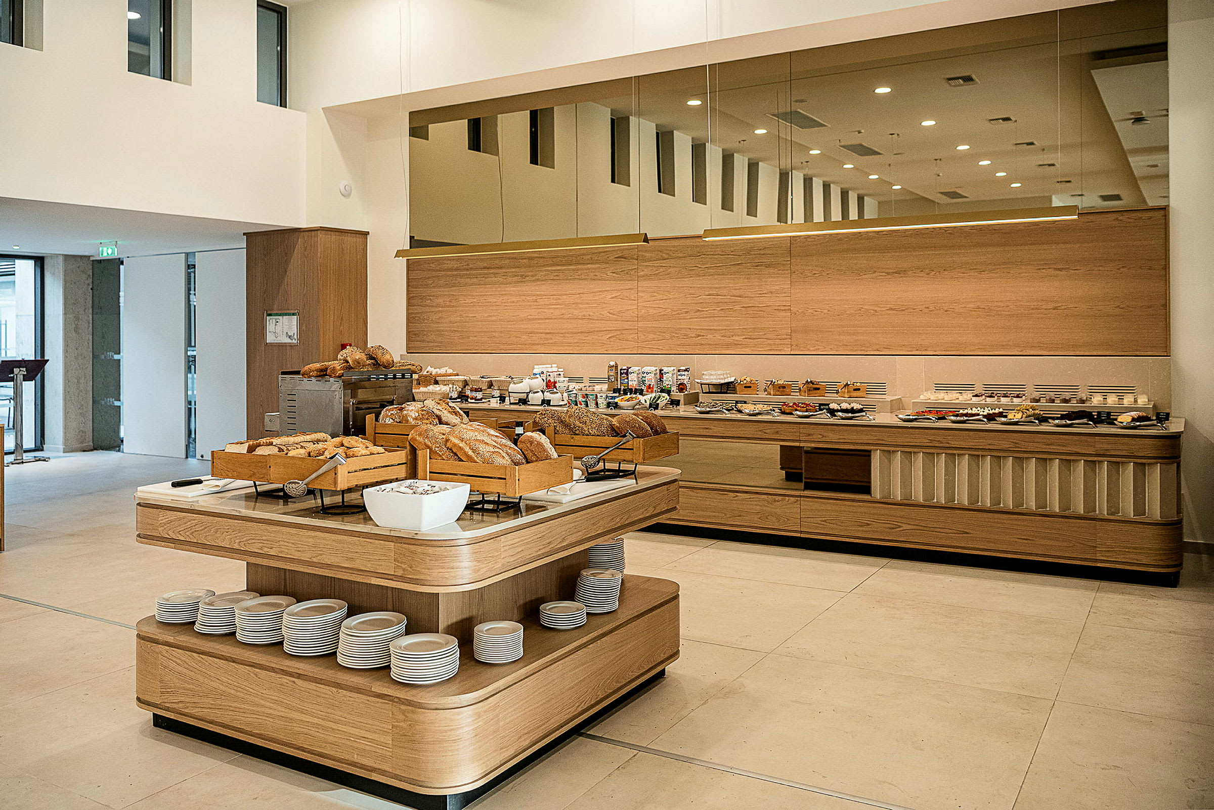 En morgenmadsbuffet med forskellige brødtyper og tilbehør opstillet i en lys og moderne spisesal. (AI-genereret tekst)