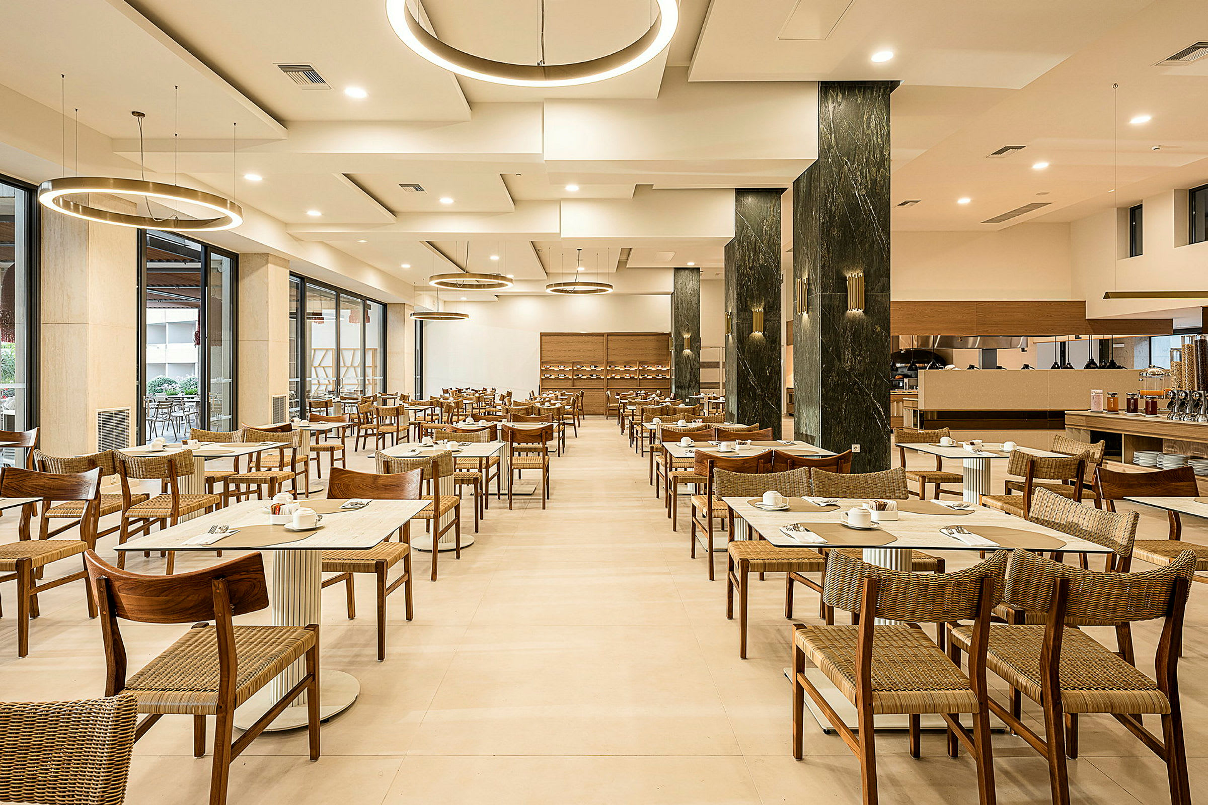 En restaurant med dækkede borde og stole, moderne loftslamper og lyst interiør. (AI-genereret tekst)