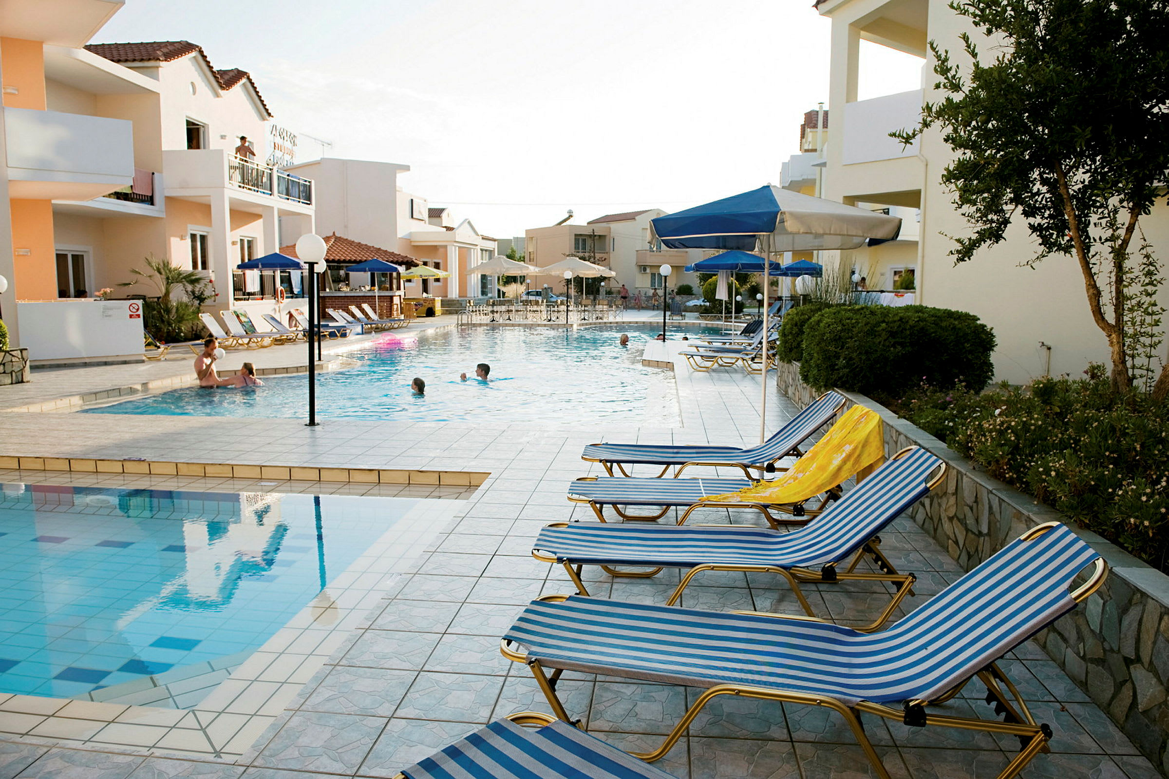 En hotelpool med liggestole og parasoller rundt om. (AI-genereret tekst)