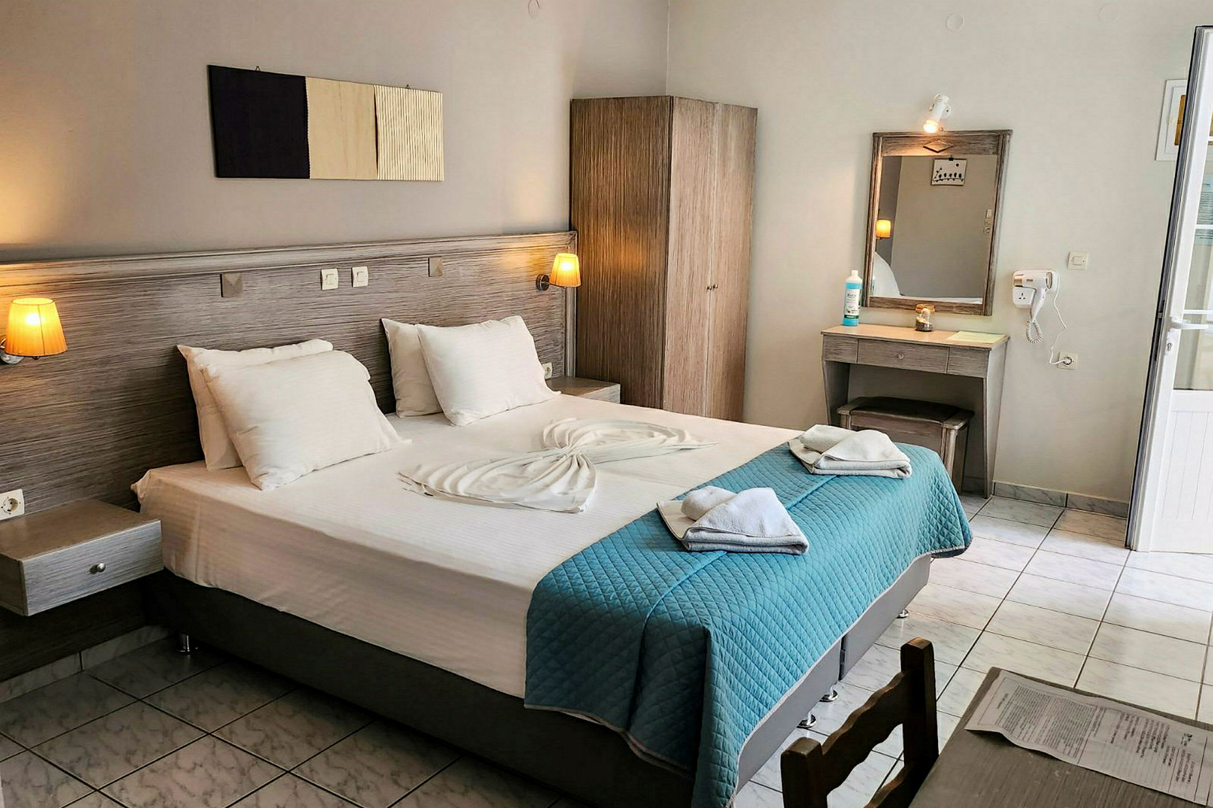 Hotelværelse med en dobbeltseng, garderobe, sminkebord og lyse tekstiler. (AI-genereret tekst)