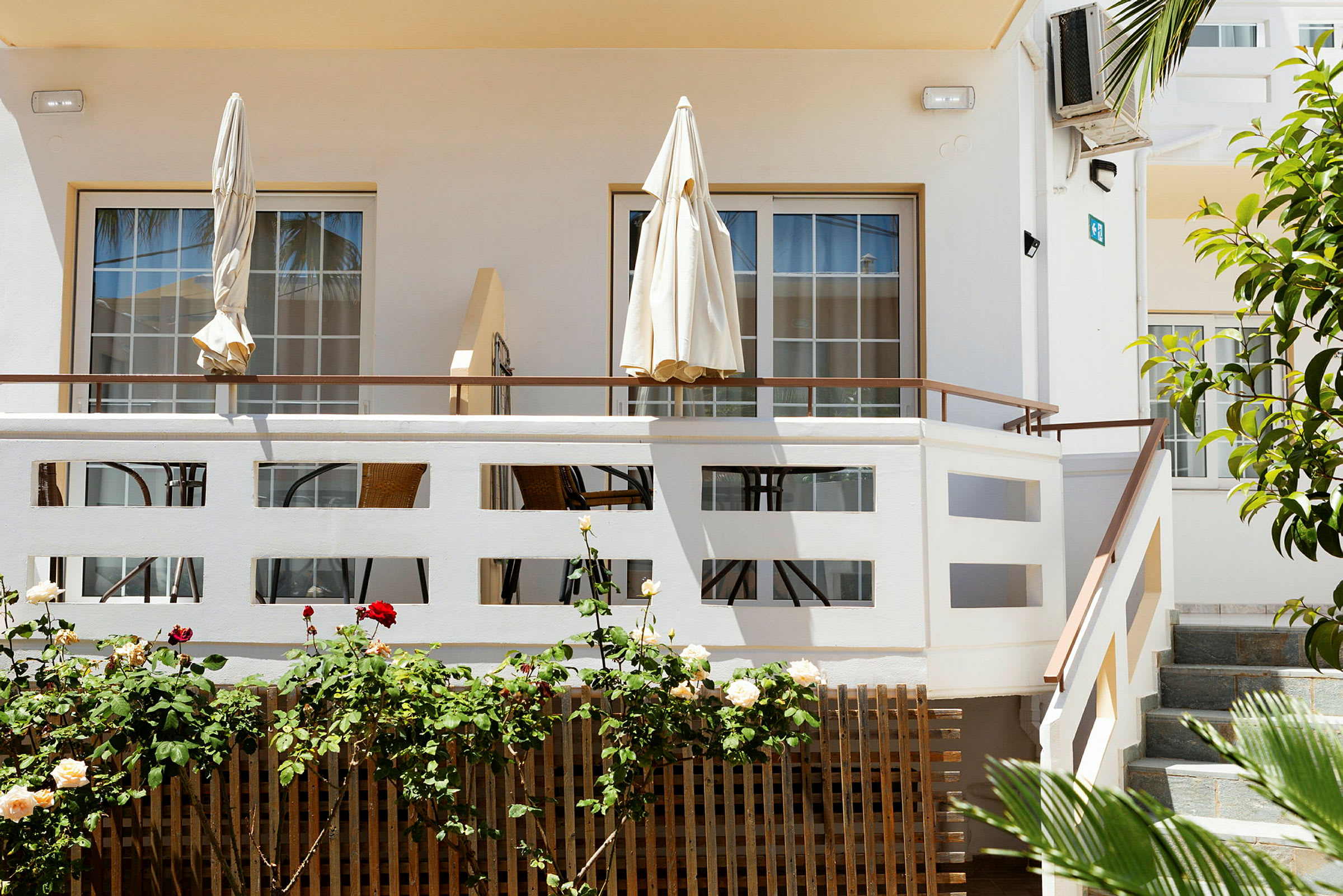 Terrasse med parasoller og havemøbler ved en lys bygning. (AI-genereret tekst)