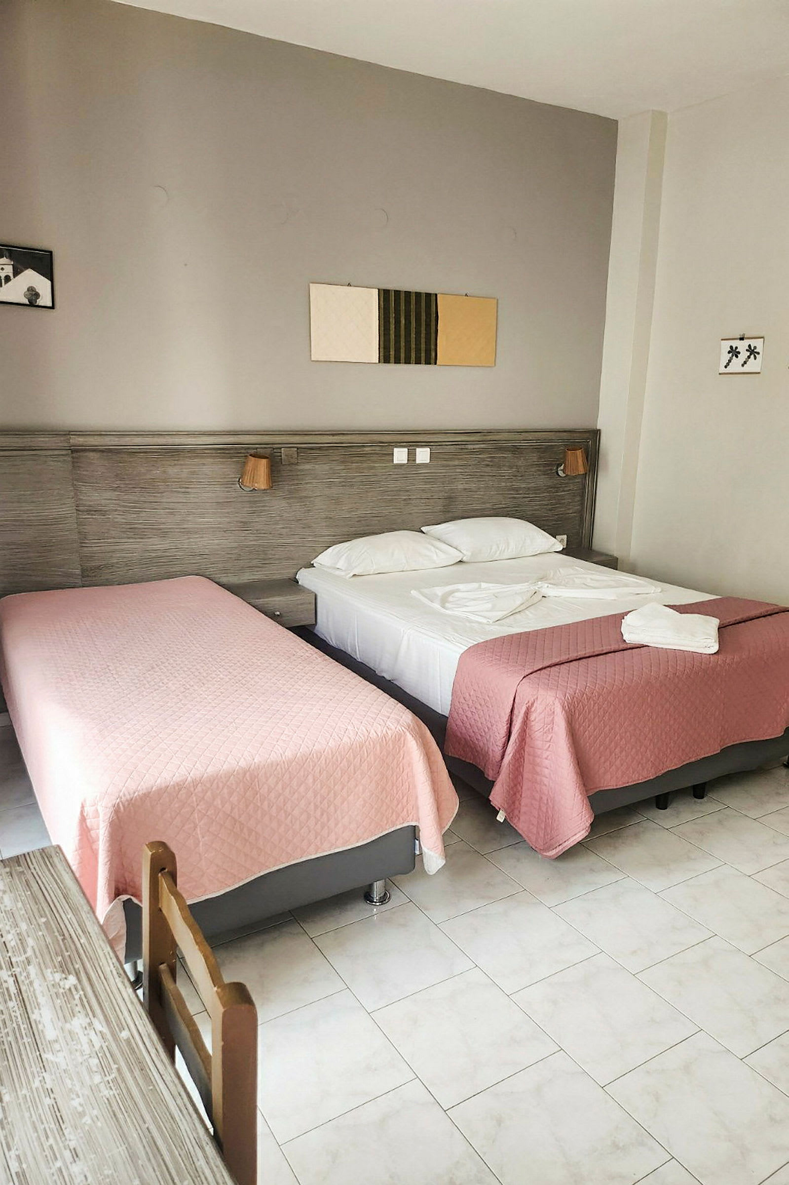 Et hotelværelse med to senge redt med lyserøde sengetæpper. (AI-genereret tekst)
