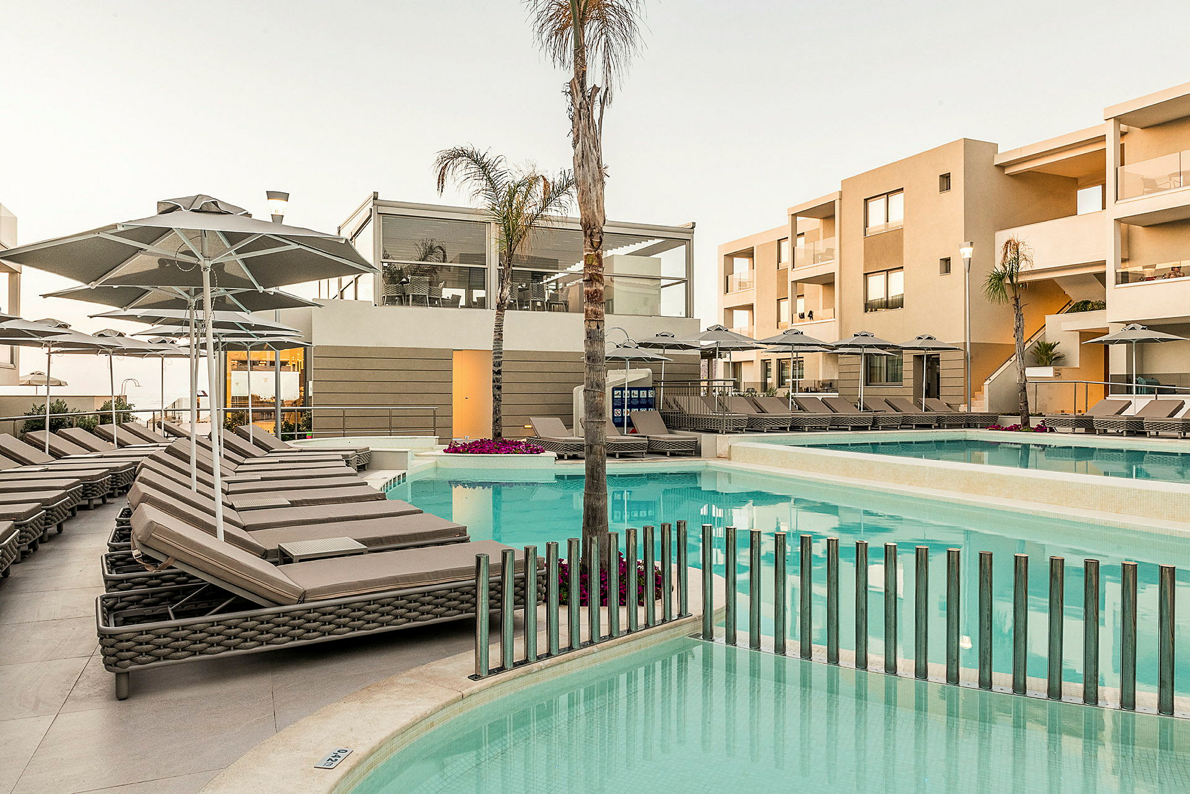 Hotellets poolområde med liggestole og parasoller. (AI-genereret tekst)