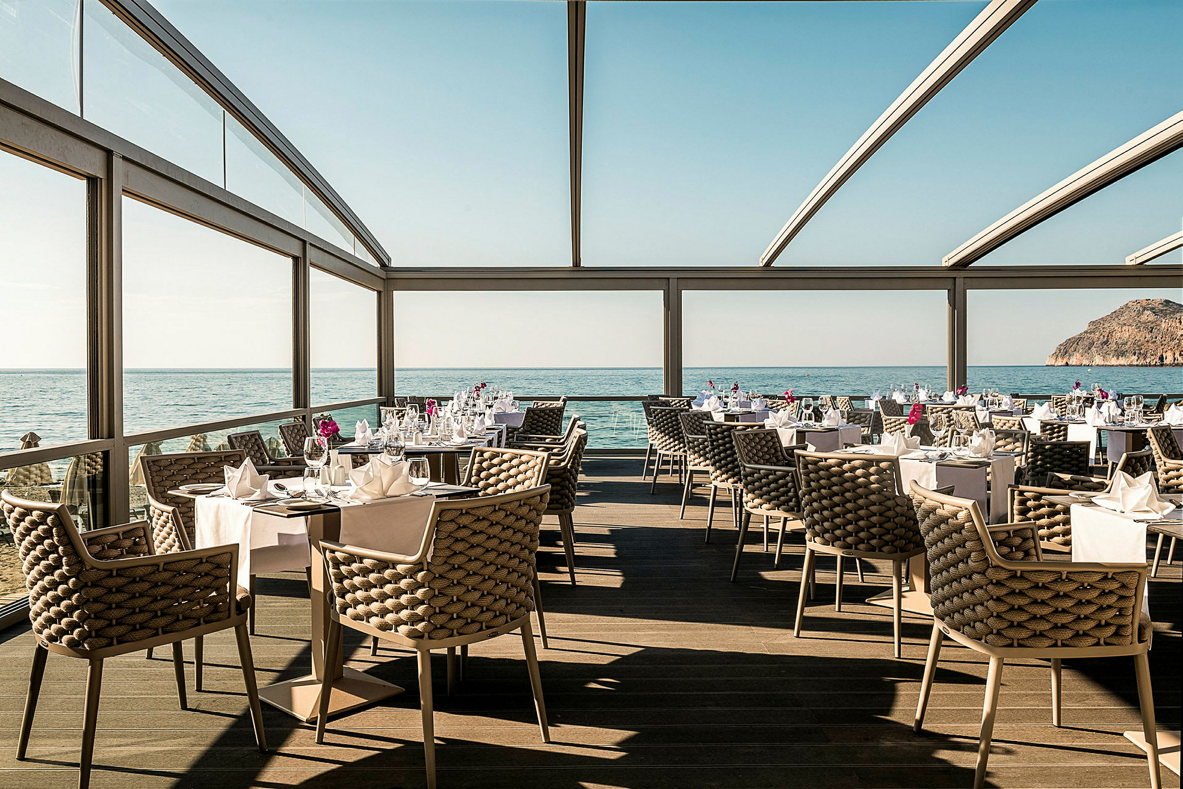 Restaurant med havudsigt, elegante møbler og dækkede borde. (AI-genereret tekst)