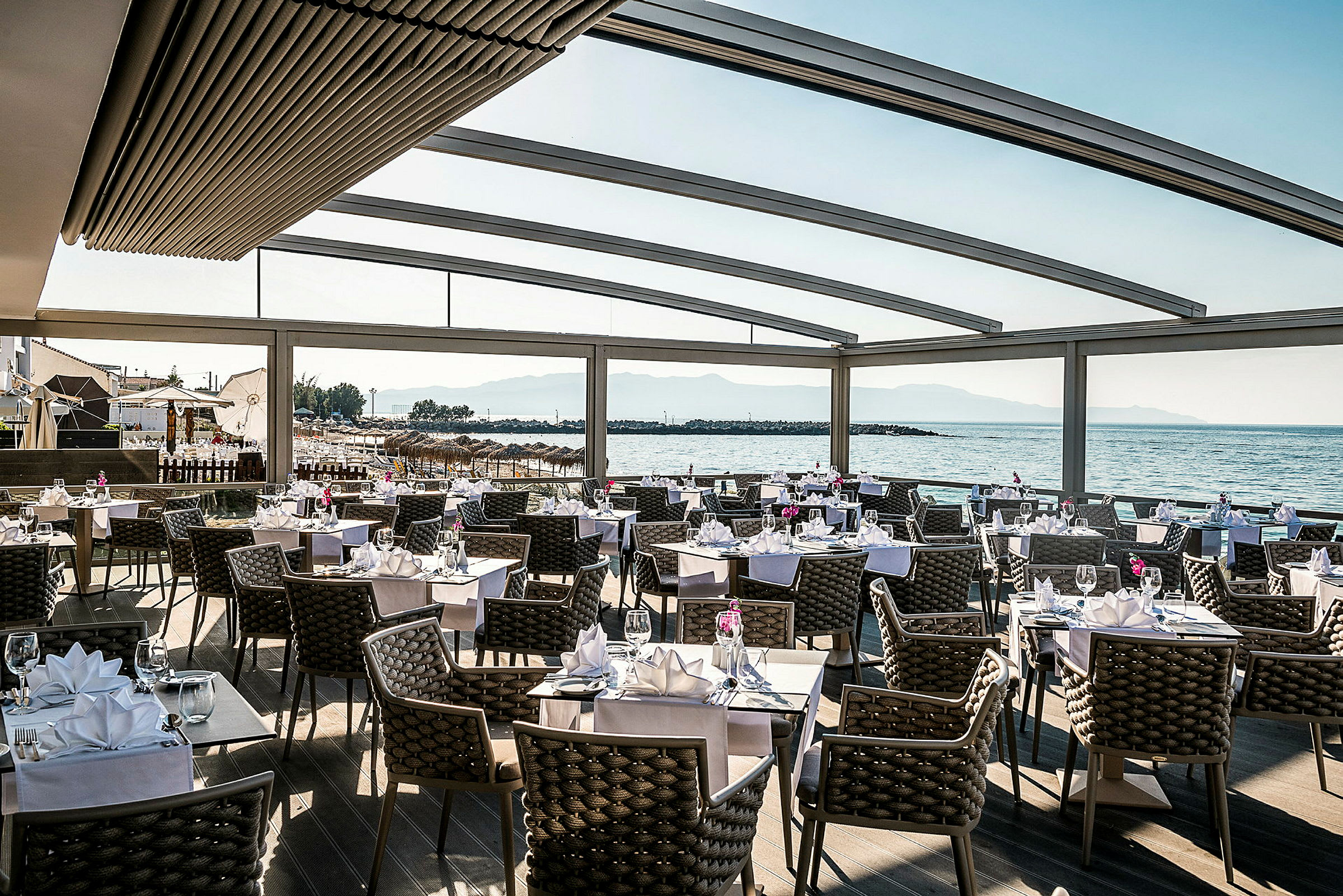 En restaurant med dækkede borde og udsigt over havet. (AI-genereret tekst)