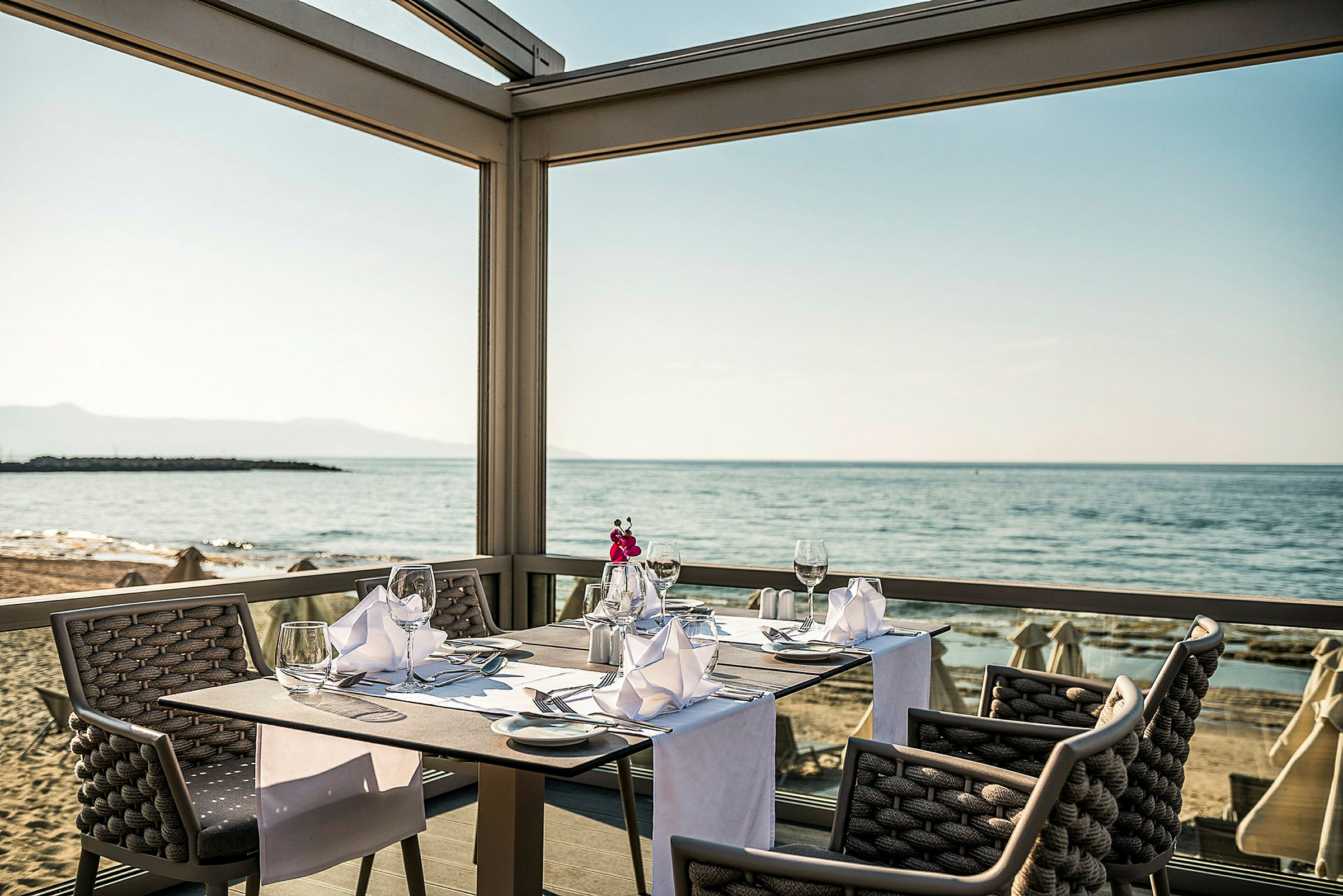 En restaurantplads ved havet med dækket bord og udsigt over stranden. (AI-genereret tekst)