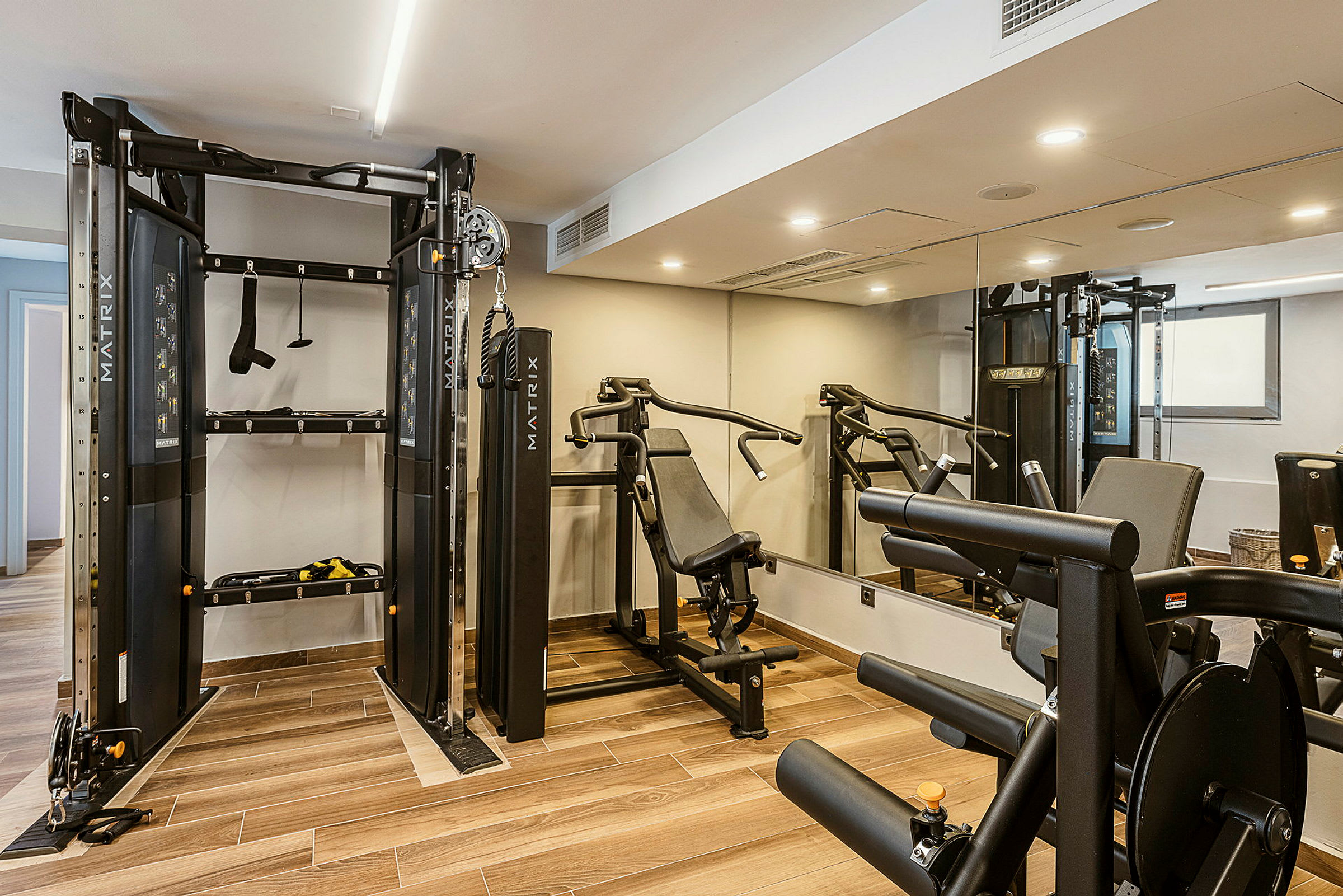 Et fitnessrum med træningsudstyr, inklusive en multigym-maskine og en bænkpres. (AI-genereret tekst)