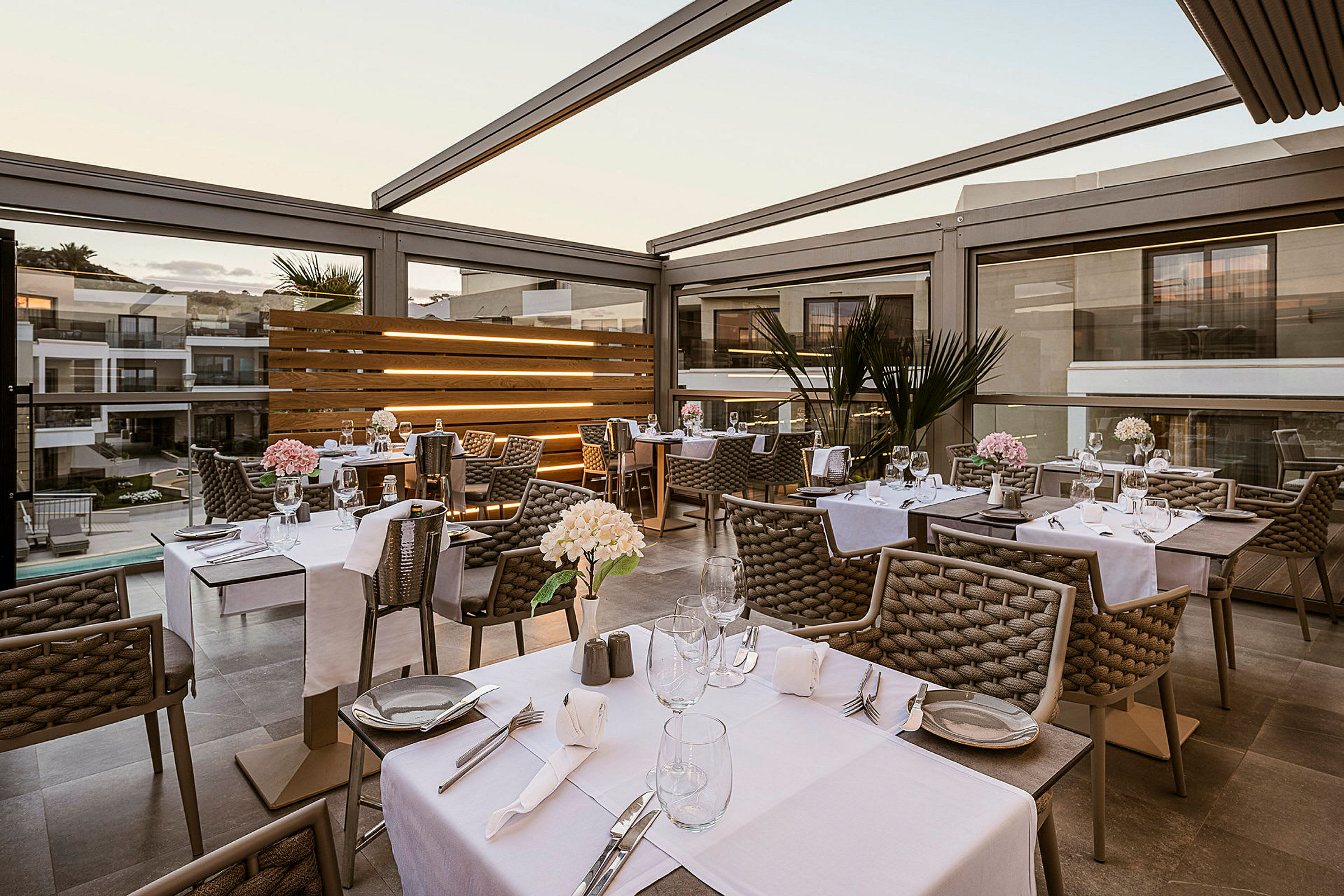 Billede af en udendørs restaurant med dækkede borde. Indretningen er moderne og elegant. (AI-genereret tekst)