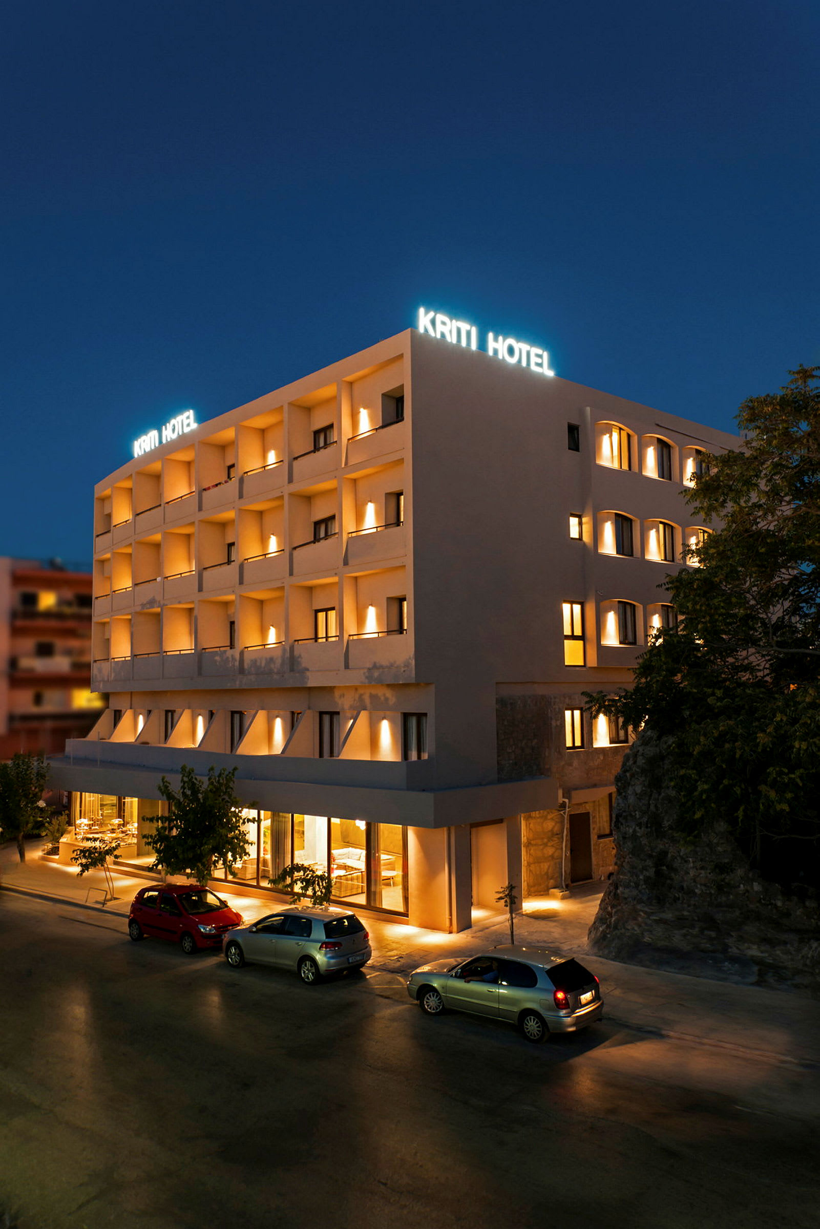 Hotelbygning om natten med oplyst skilt og facade. (AI-genereret tekst)
