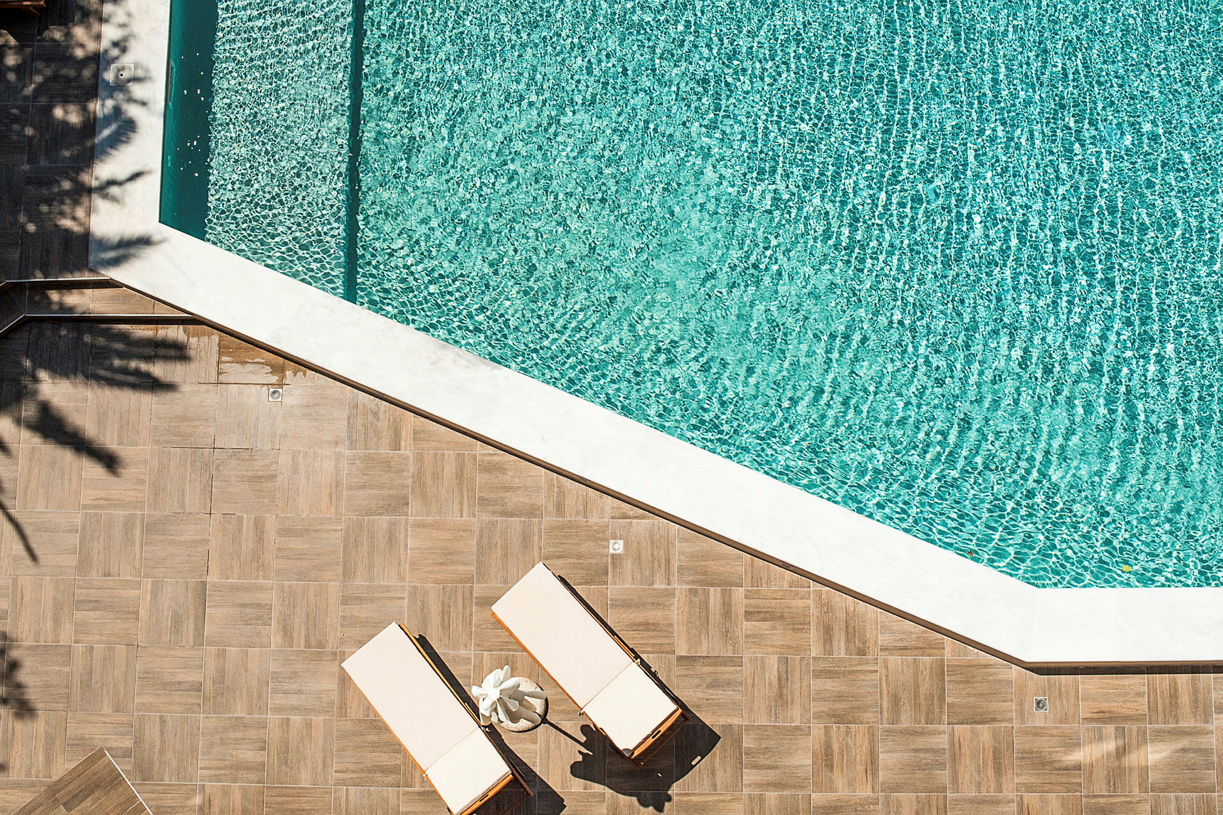 To solsenge på et trægulv ved siden af en swimmingpool. (AI-genereret tekst)