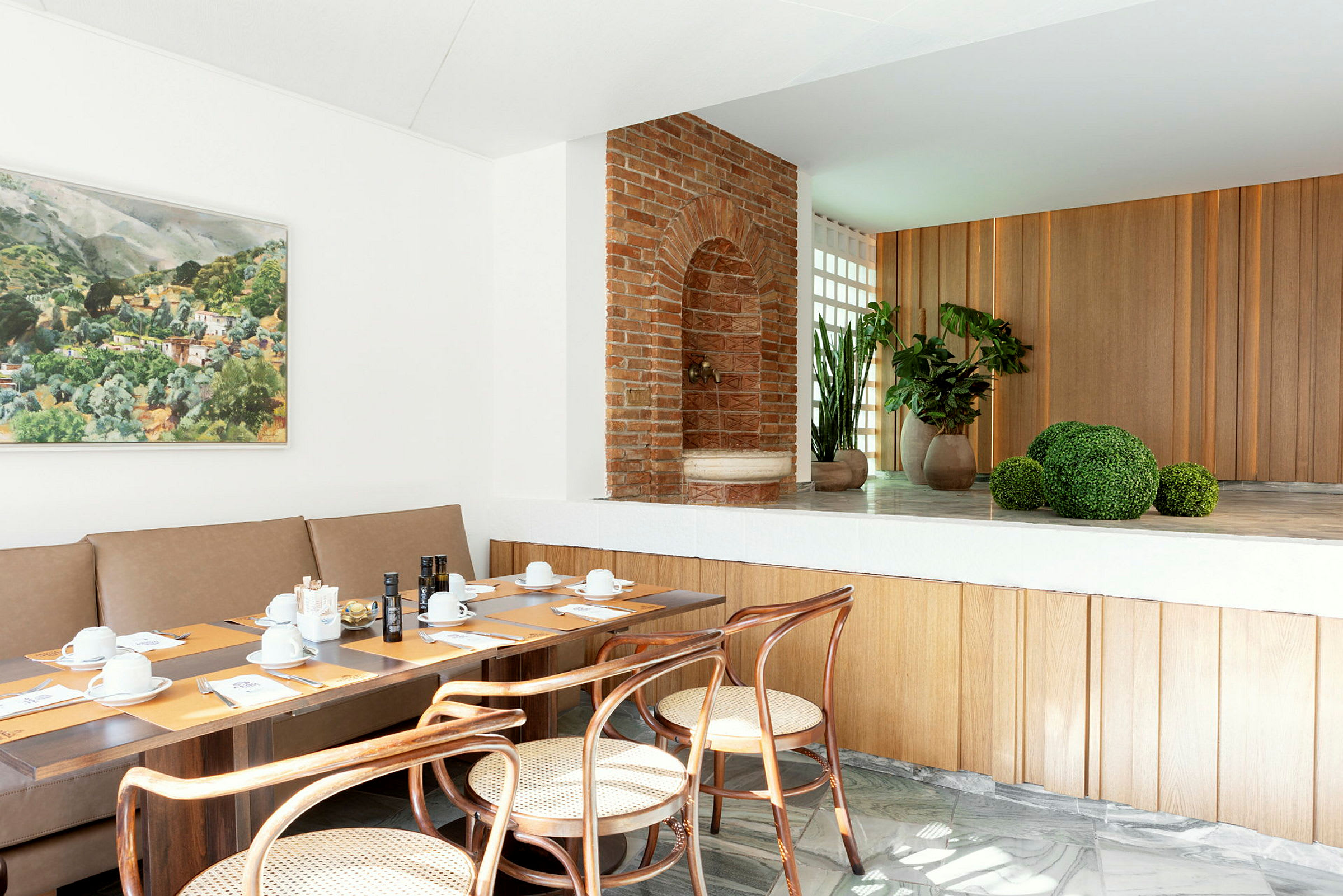 Et moderne restaurantmiljø med borde dækket til et måltid, kunst på væggen og planter i baggrunden. (AI-genereret tekst)