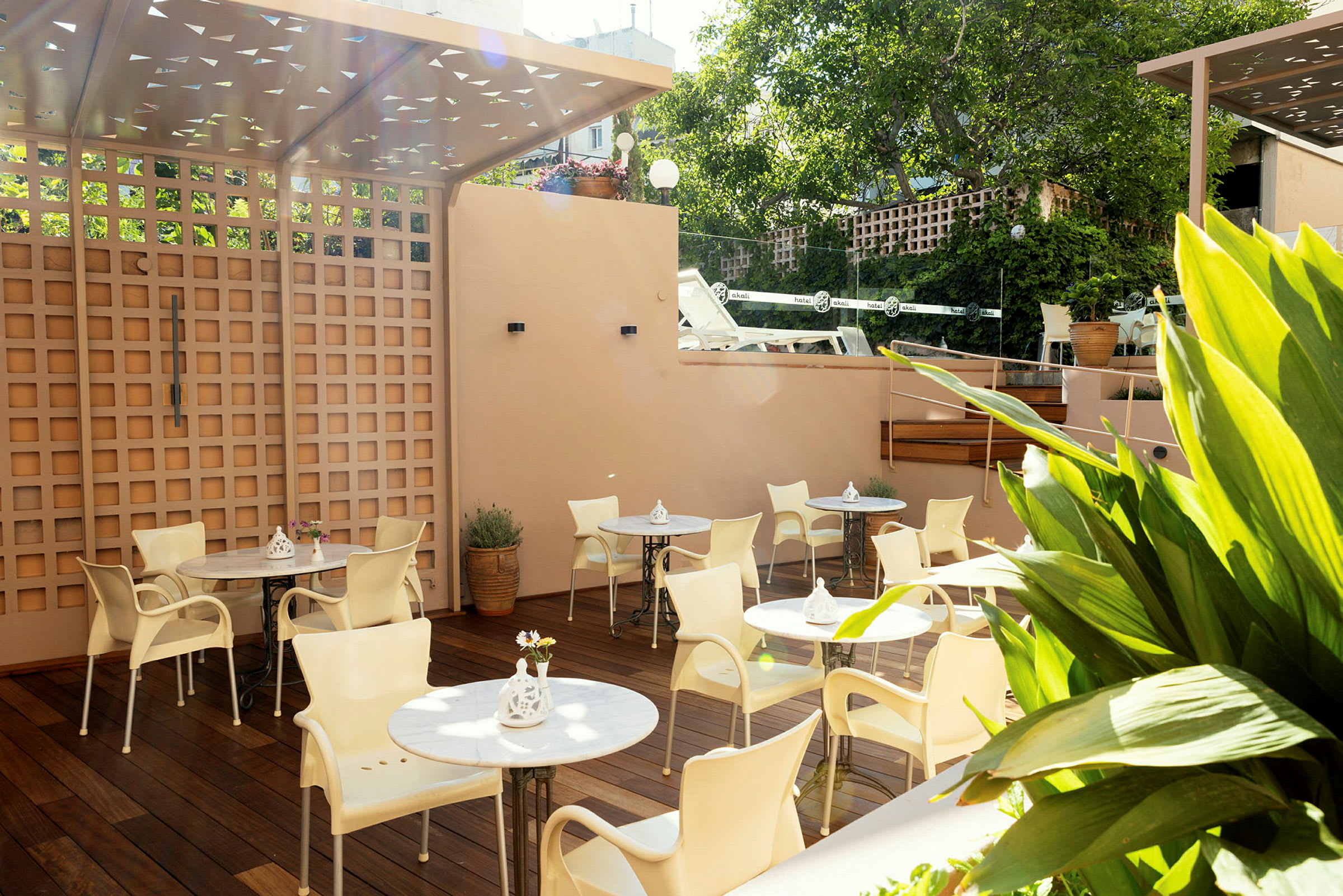 En terrasse med borde og stole, omgivet af planter. (AI-genereret tekst)