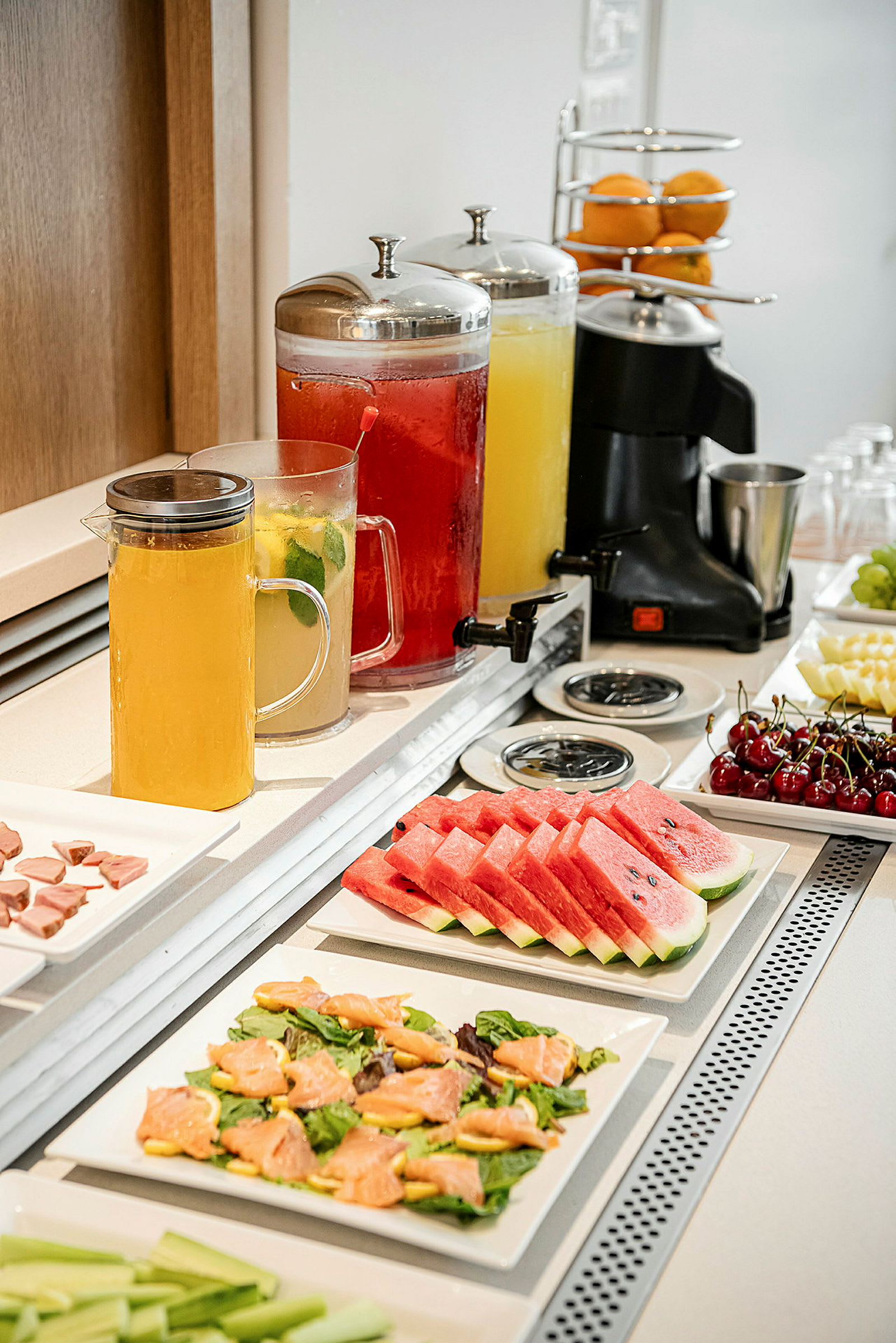 Buffet med frugtskiver, salatretter og karafler med drikke. (AI-genereret tekst)