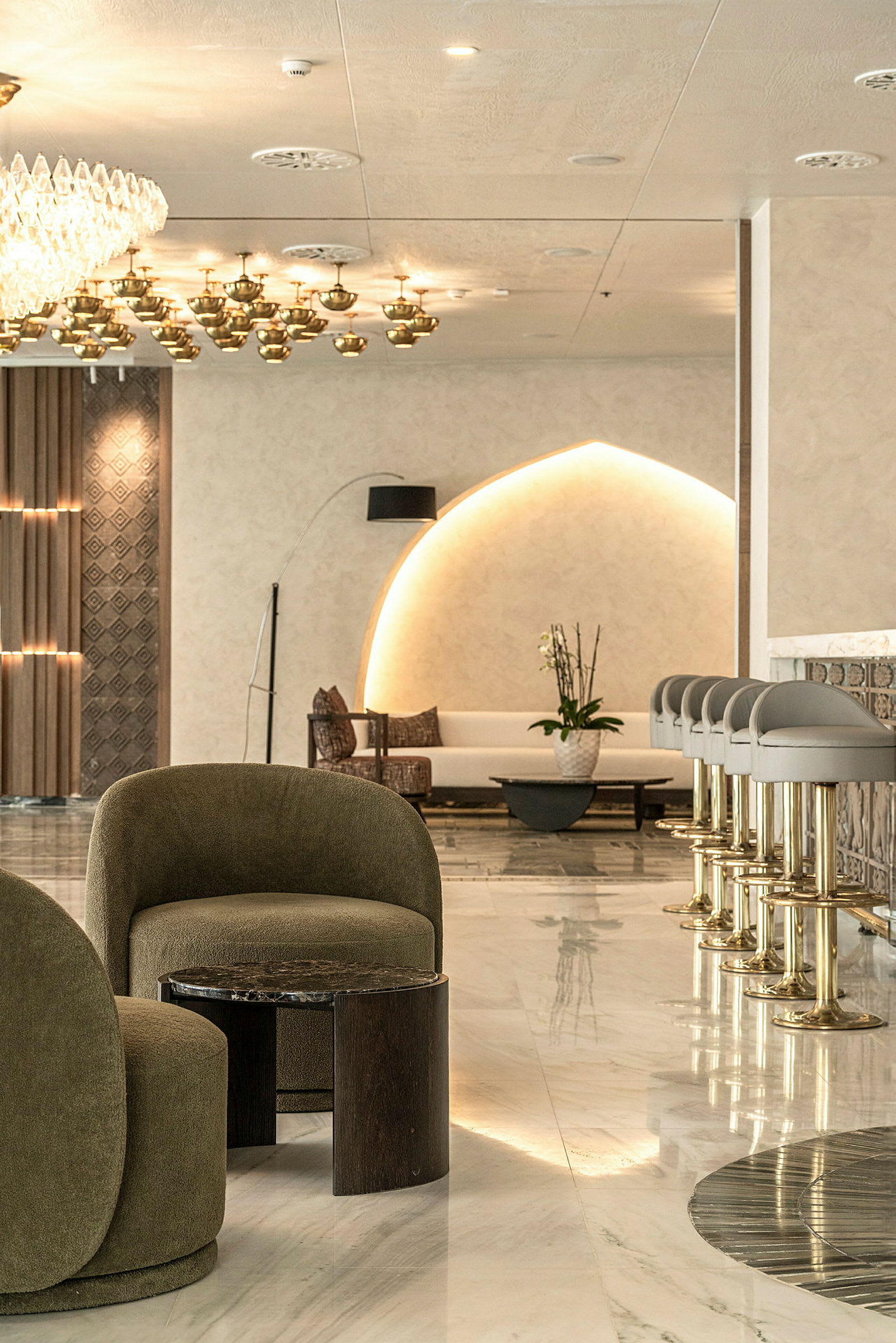 En elegant hotellobby med moderne møbler, inklusive grønne lænestole og en række barstole. (AI-genereret tekst)