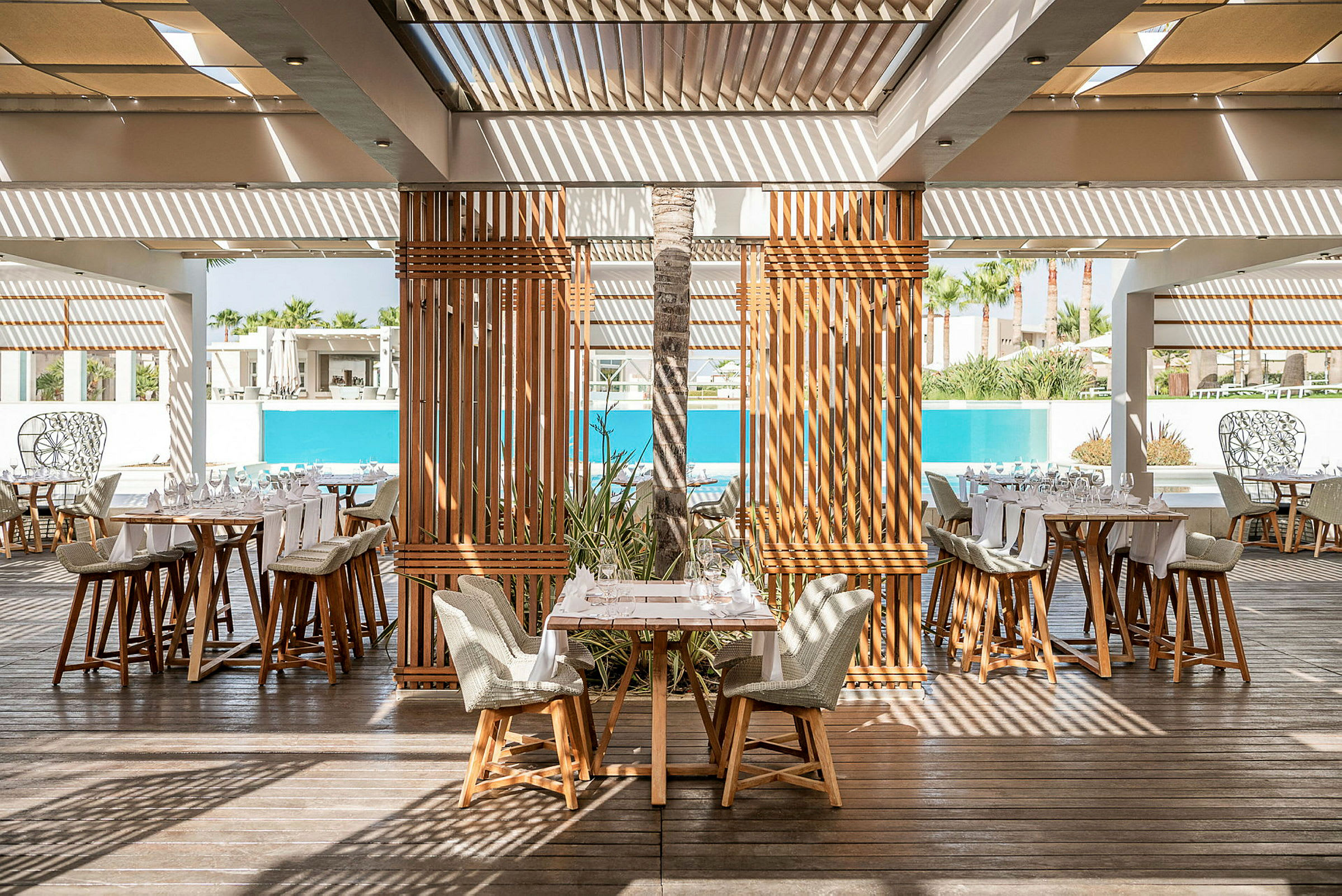 Restaurant med træmøbler og udsigt til en pool. (AI-genereret tekst)