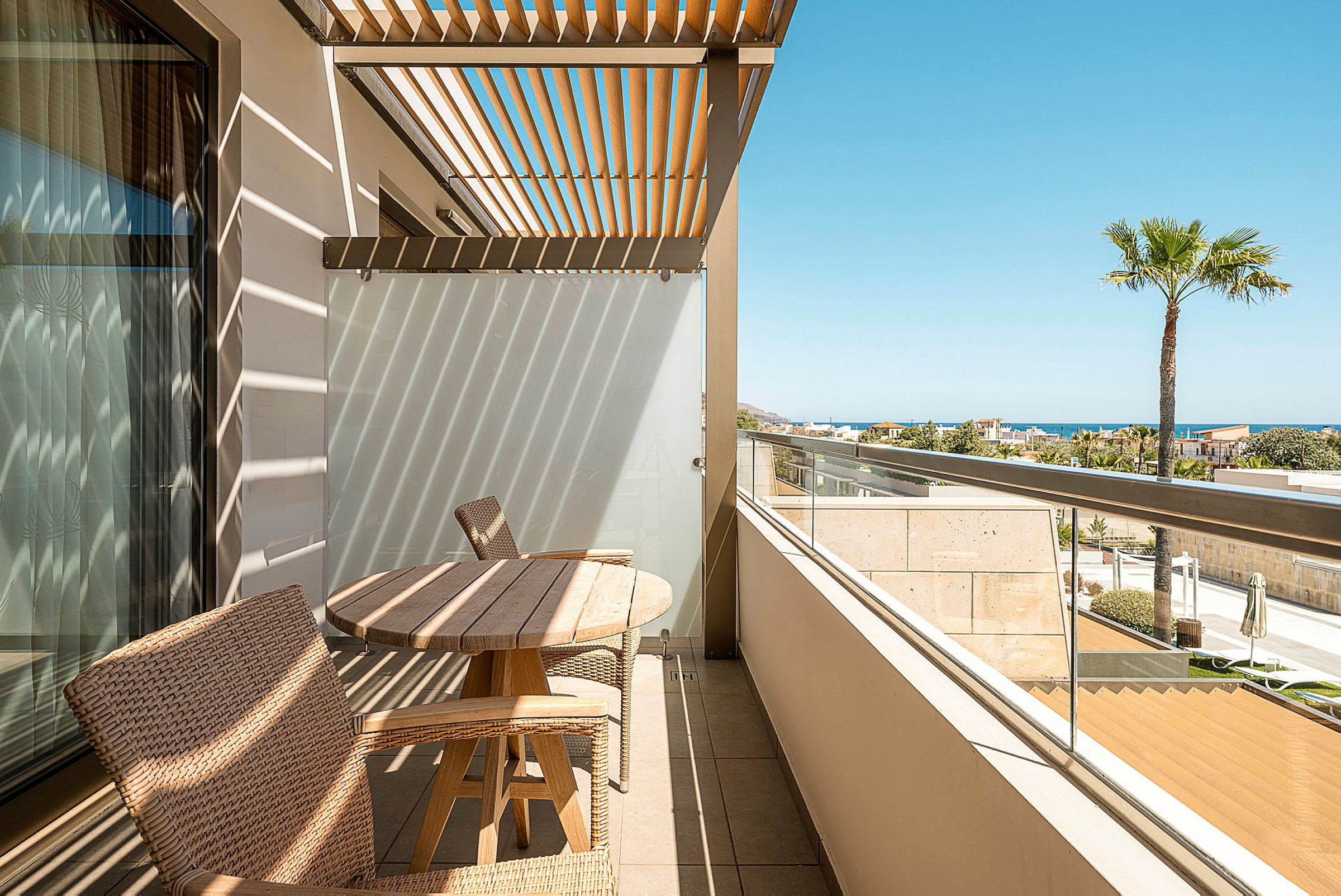 En terrasse med havemøbler af træ og pergola, med havudsigt i baggrunden. (AI-genereret tekst)