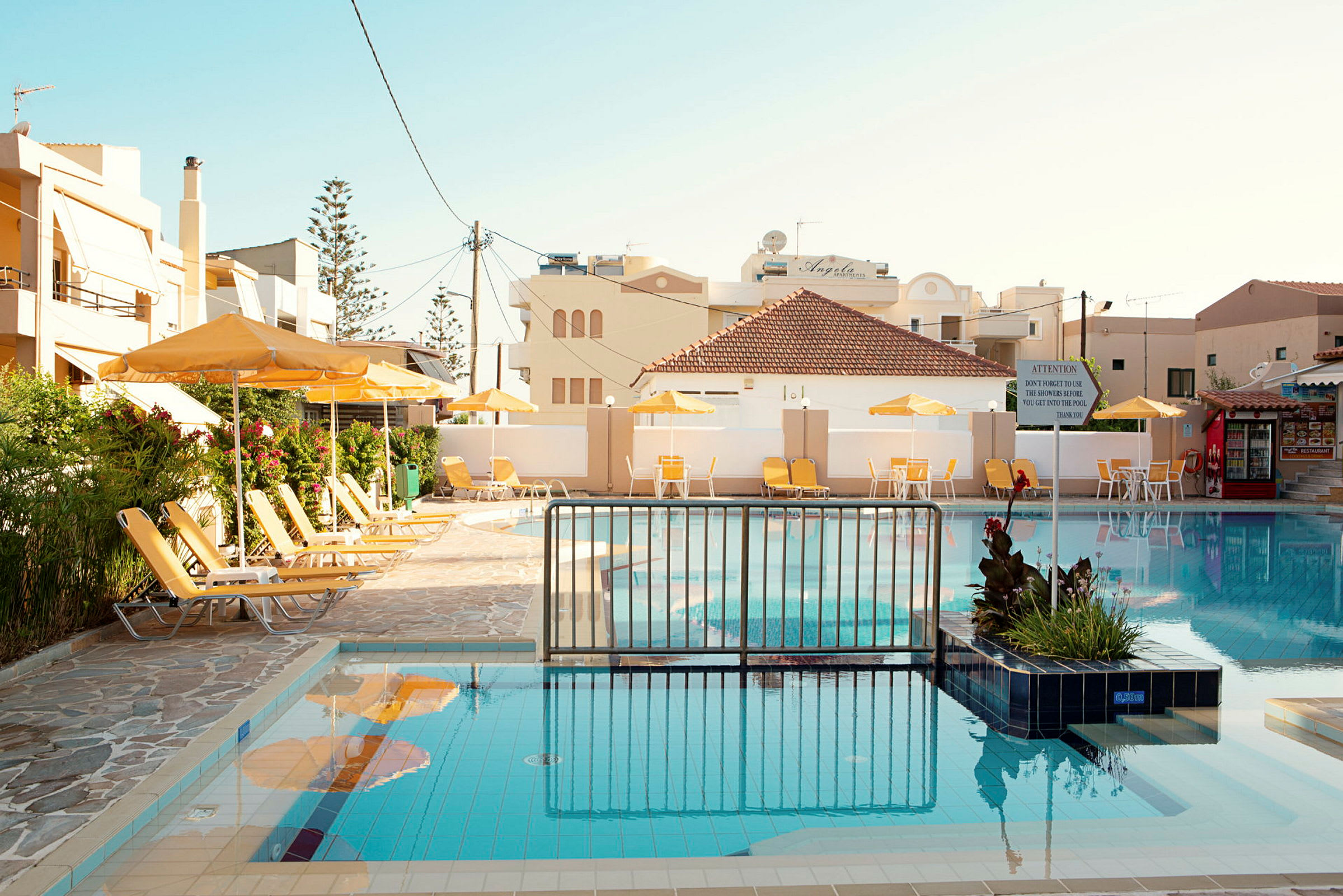 Billede af en hotelpool omgivet af liggestole og parasoller. (AI-genereret tekst)