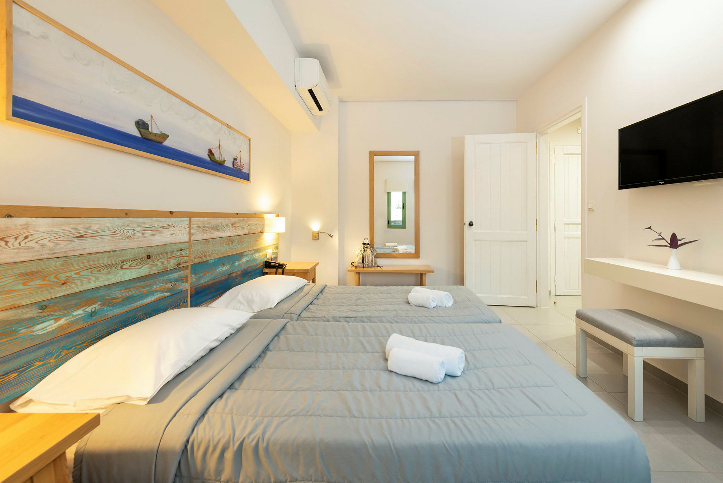 To enkeltsenge med grå sengetæpper i et lyst hotelværelse. (AI-genereret tekst)