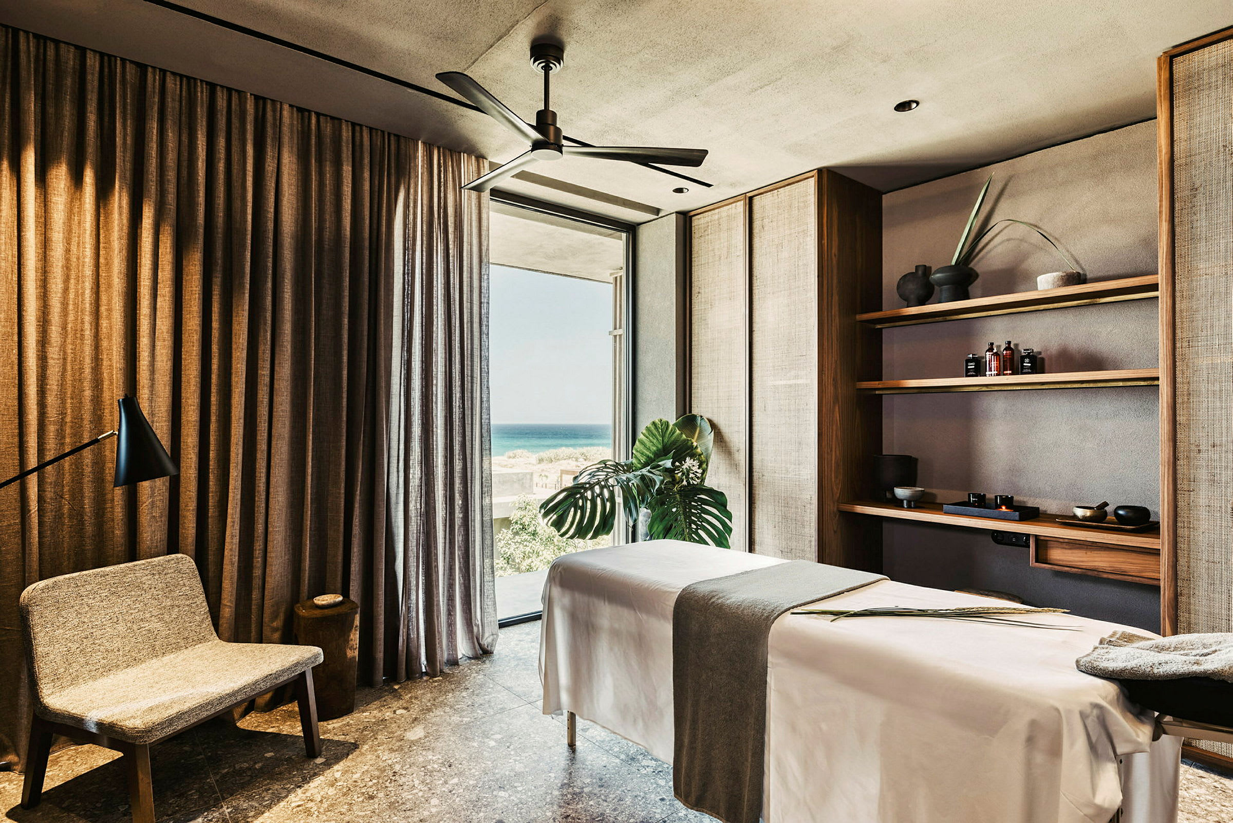 Spa-rum med massagebriks, stol og hylder med produkter. (AI-genereret tekst)