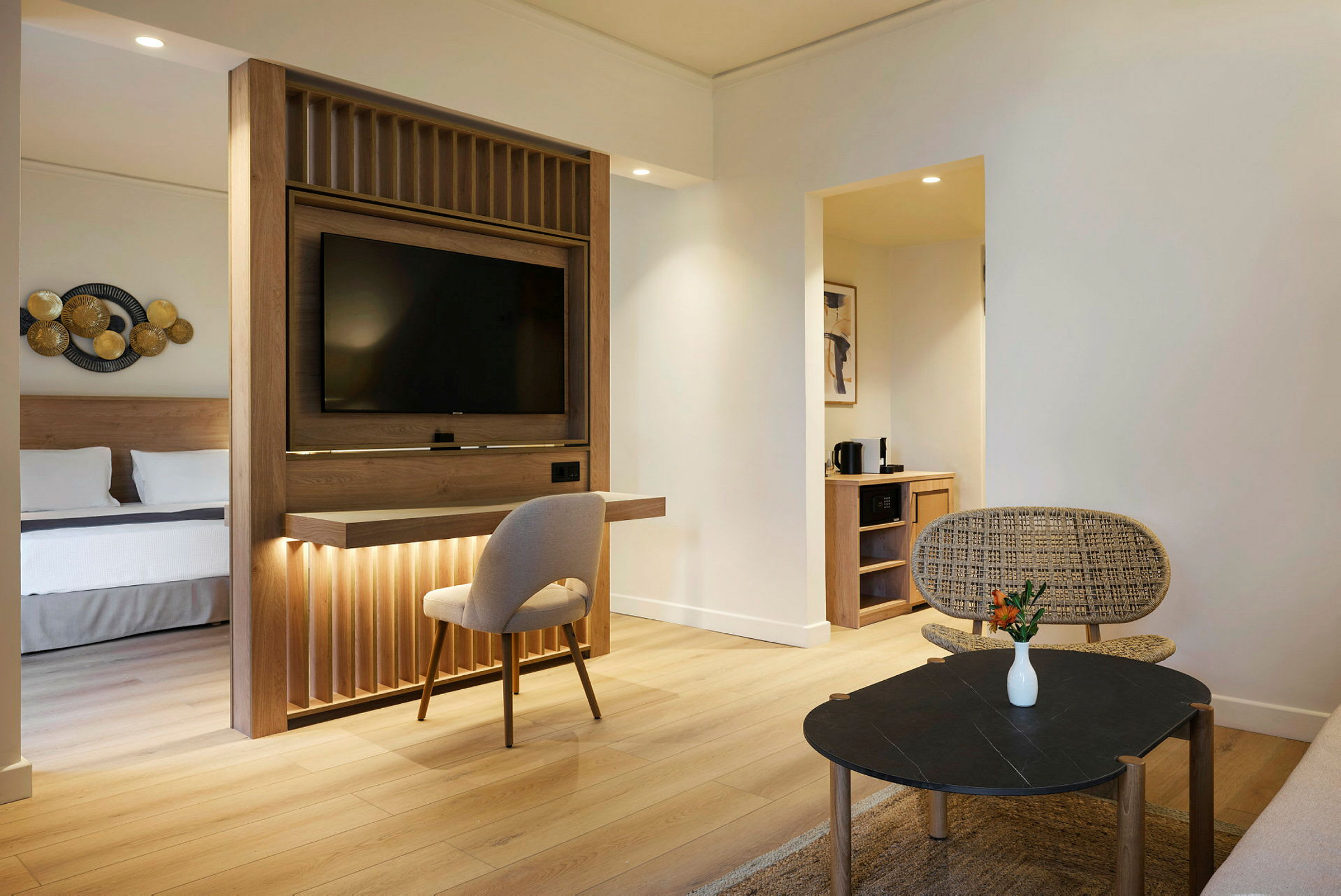 Hotelværelse med moderne indretning, separat soveområde og opholdsstue med siddepladser og bord. (AI-genereret tekst)