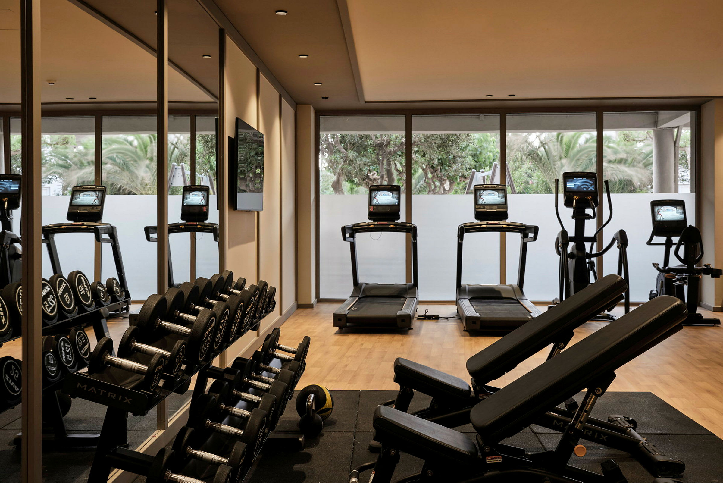 Et fitnesscenter med træningsudstyr, herunder løbebånd og håndvægte. (AI-genereret tekst)