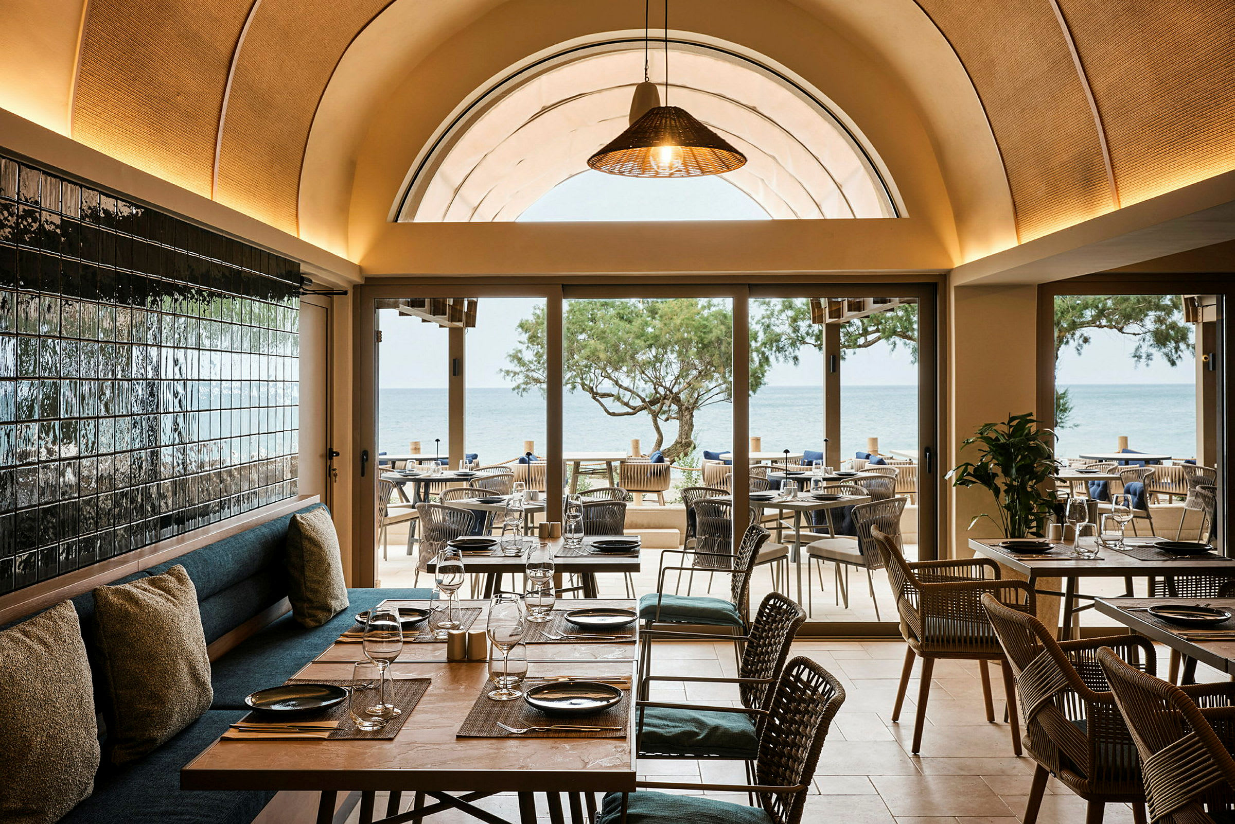 Restaurant med udsigt over havet, møbler i træ og glasdetaljer. (AI-genereret tekst)