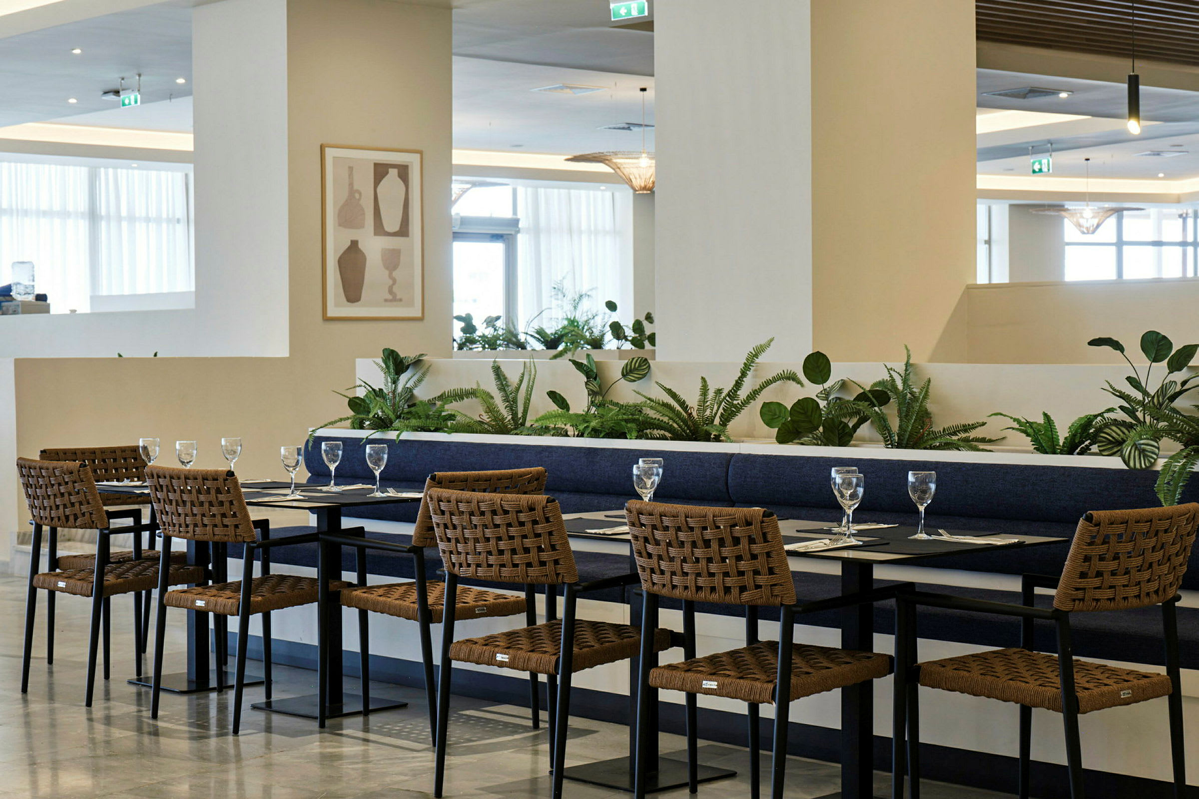 Spiseområde med borde og stole i moderne stil, omgivet af grønne planter. (AI-genereret tekst)
