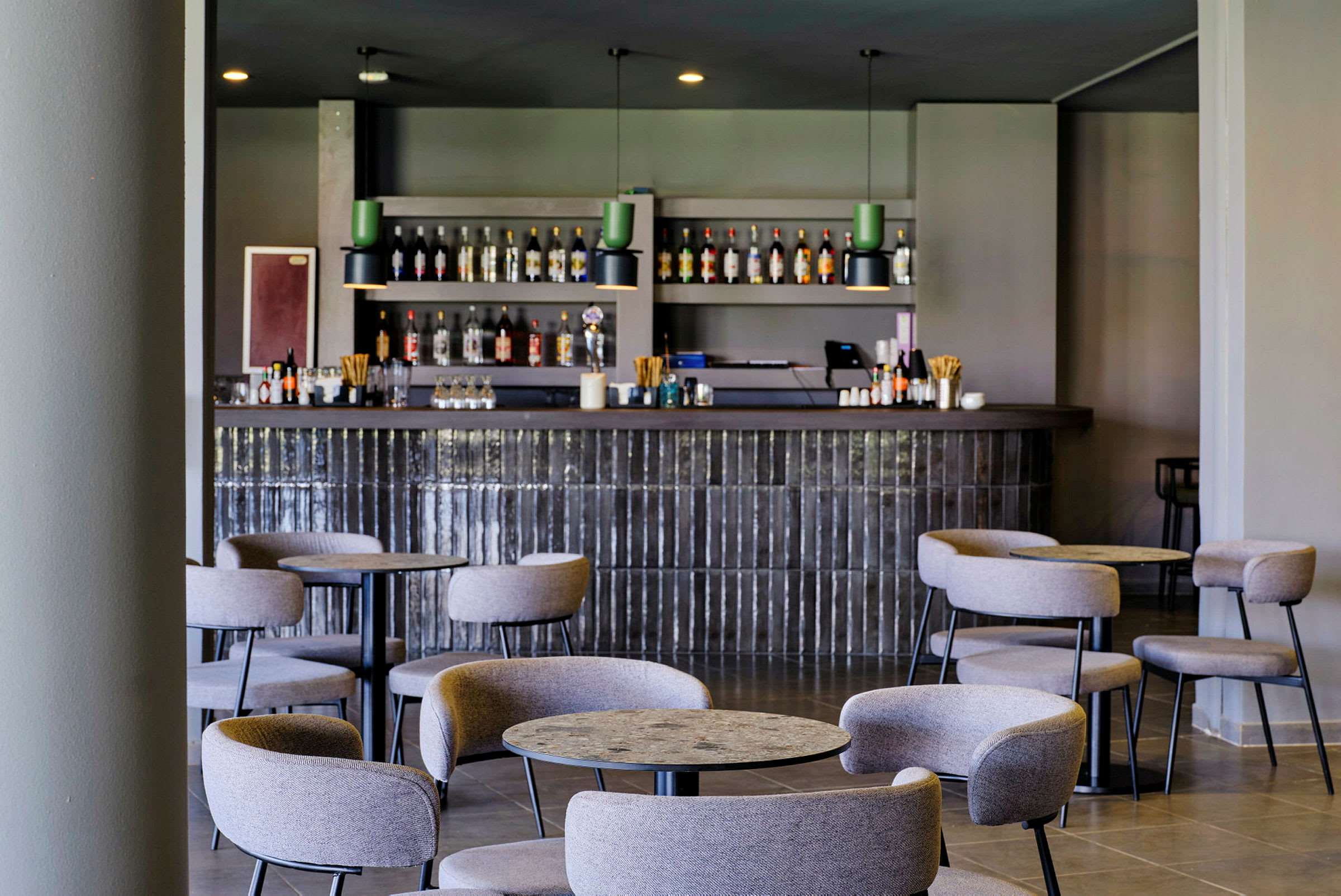 En hotelbar med tomme stole og borde foran. (AI-genereret tekst)