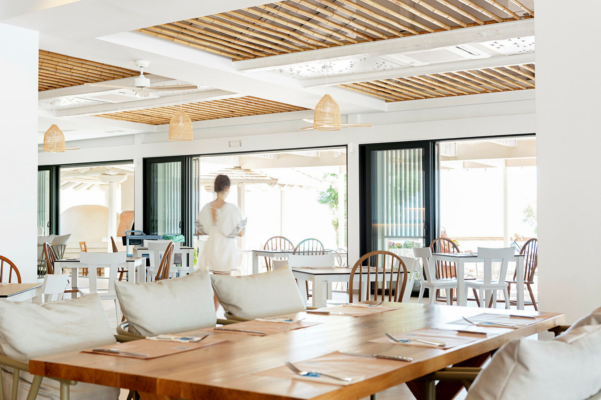Interiør af en restaurant med borde, stole og en person i bevægelse. (AI-genereret tekst)