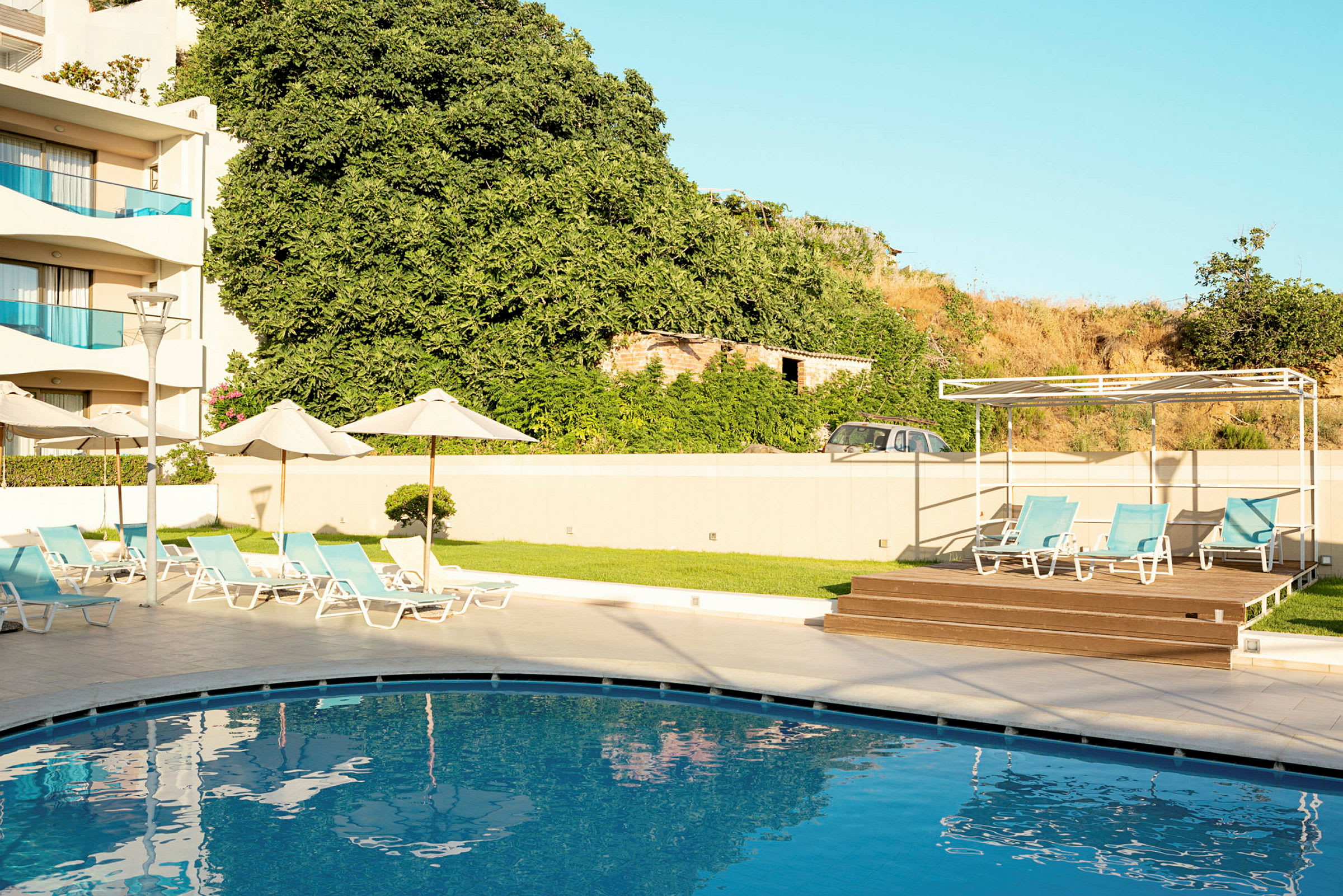 En swimmingpool med liggestole i en hotelmiljø. (AI-genereret tekst)