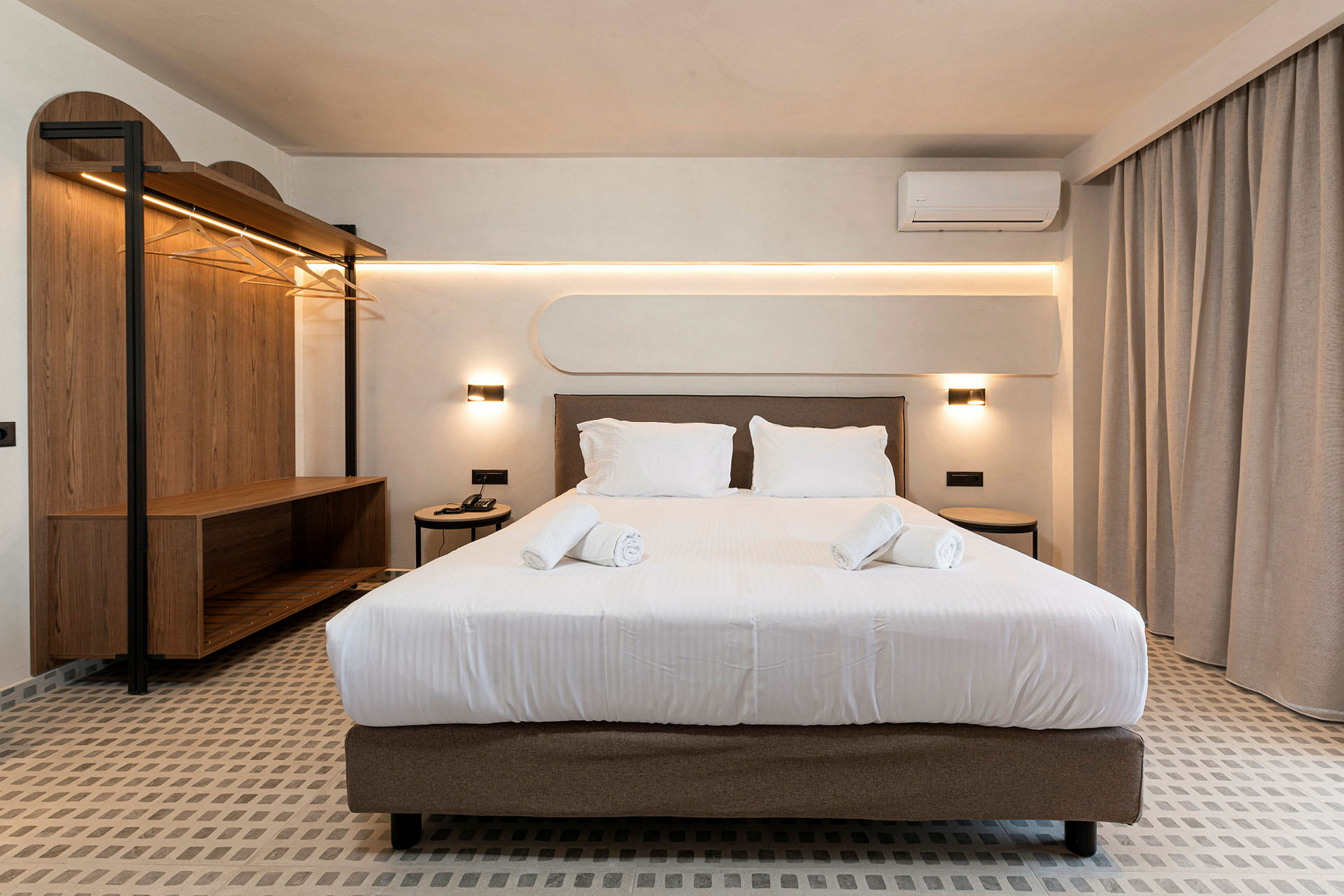 Et hotelværelse med en dobbeltseng ved siden af et sidebord og en åben garderobe. (AI-genereret tekst)